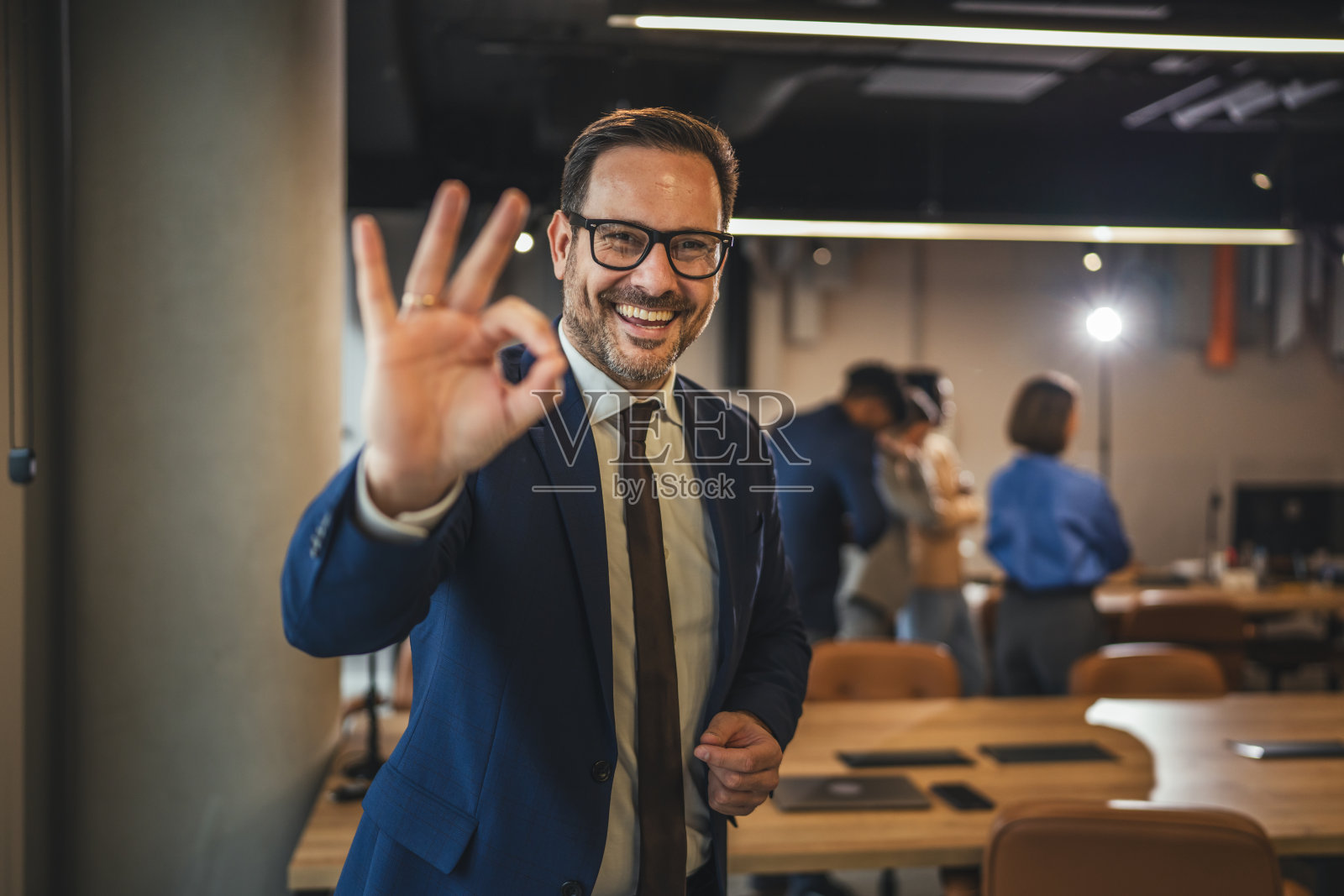 快乐的商人在办公室里打出OK手势照片摄影图片