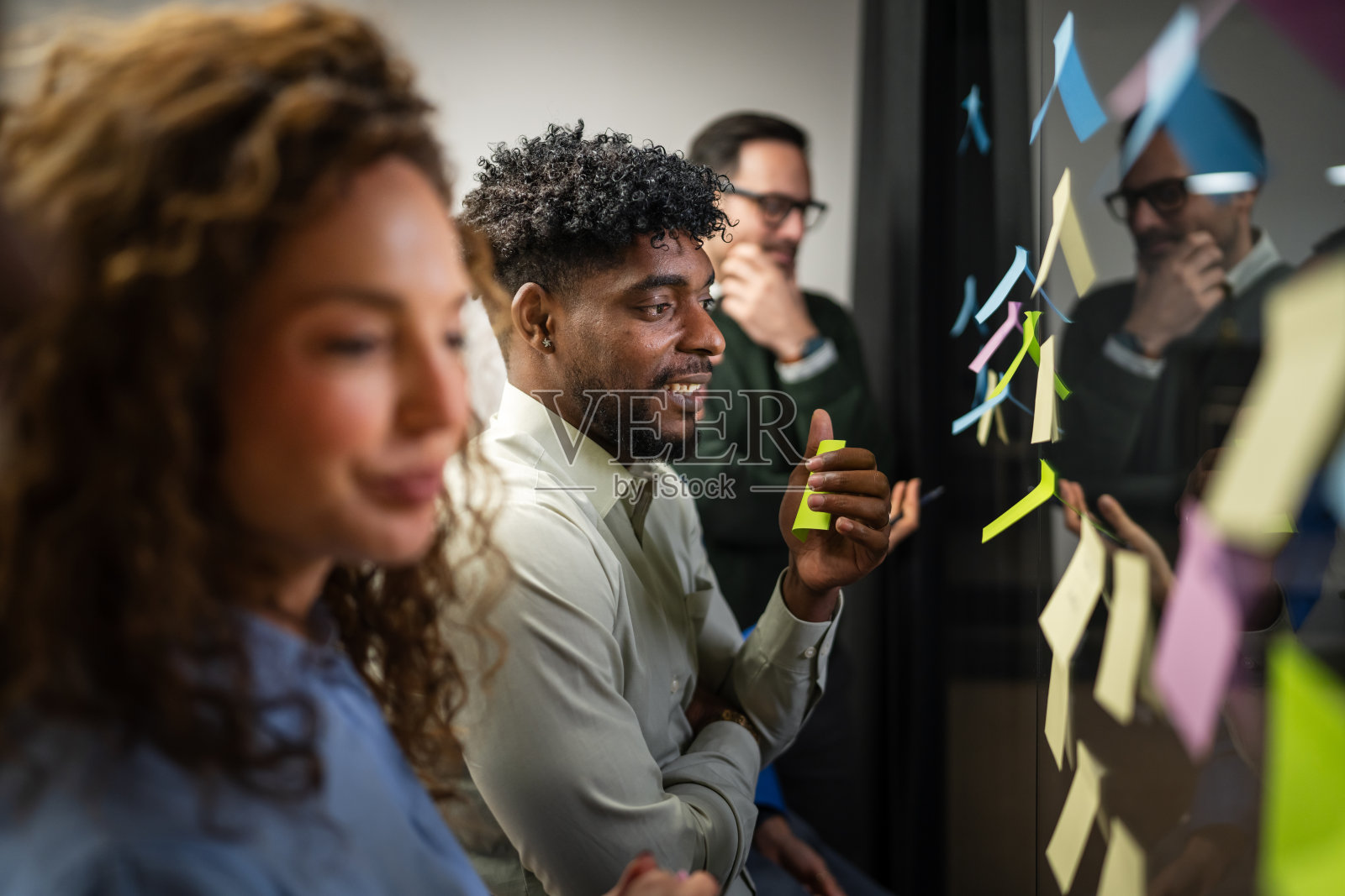 多元化的商业人士在玻璃墙上用便利贴集思广益照片摄影图片