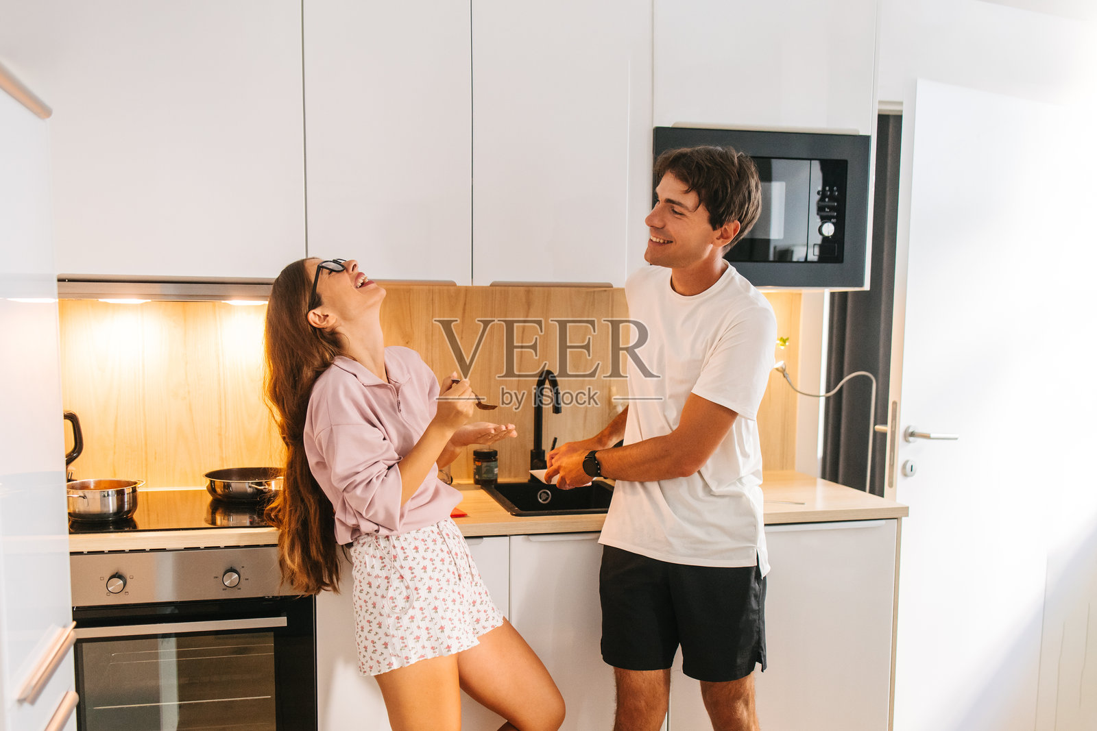 一对快乐的夫妇在现代家庭厨房里一起大笑照片摄影图片