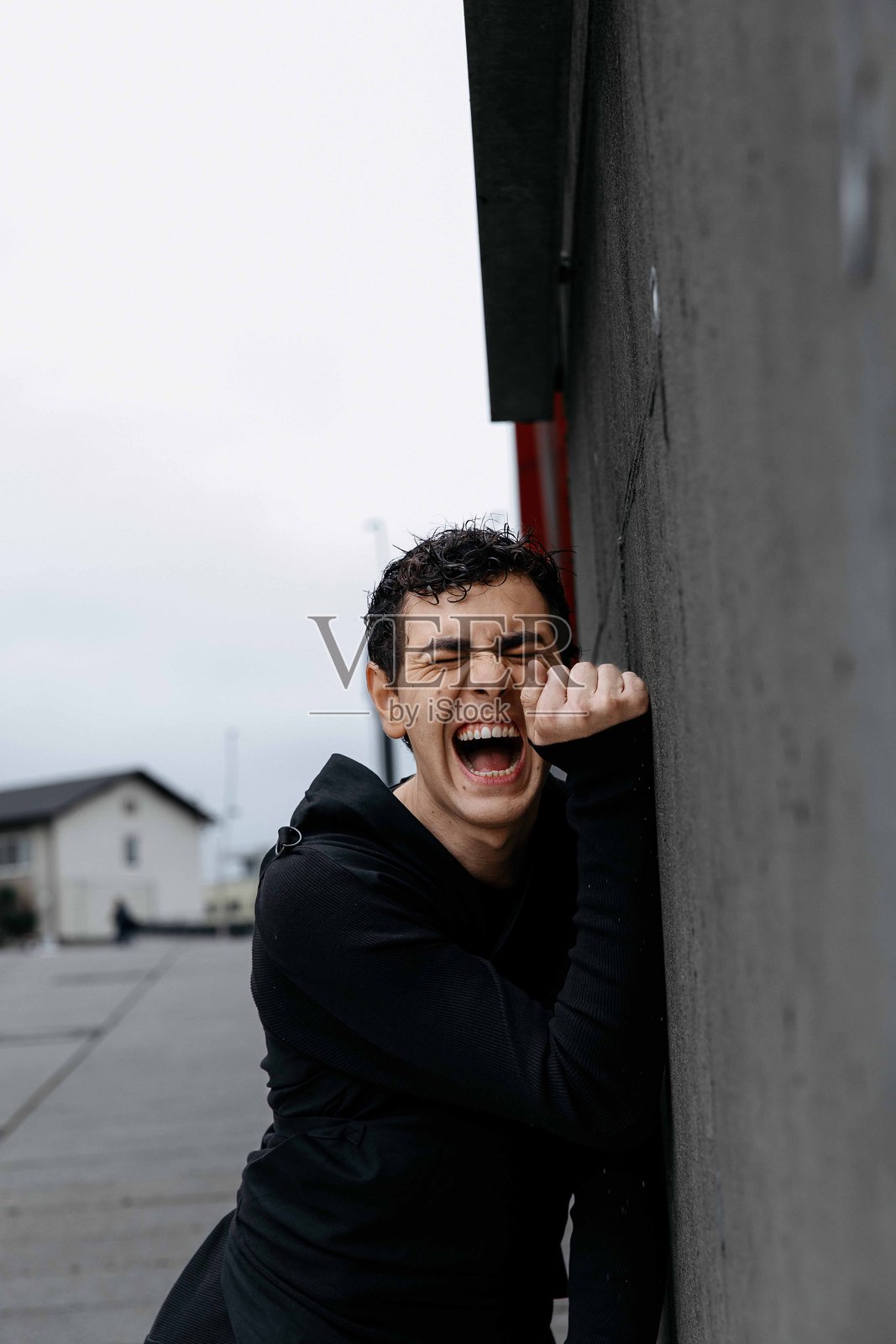 年轻的高加索男性在城市墙壁前展现出充满激情的表情照片摄影图片