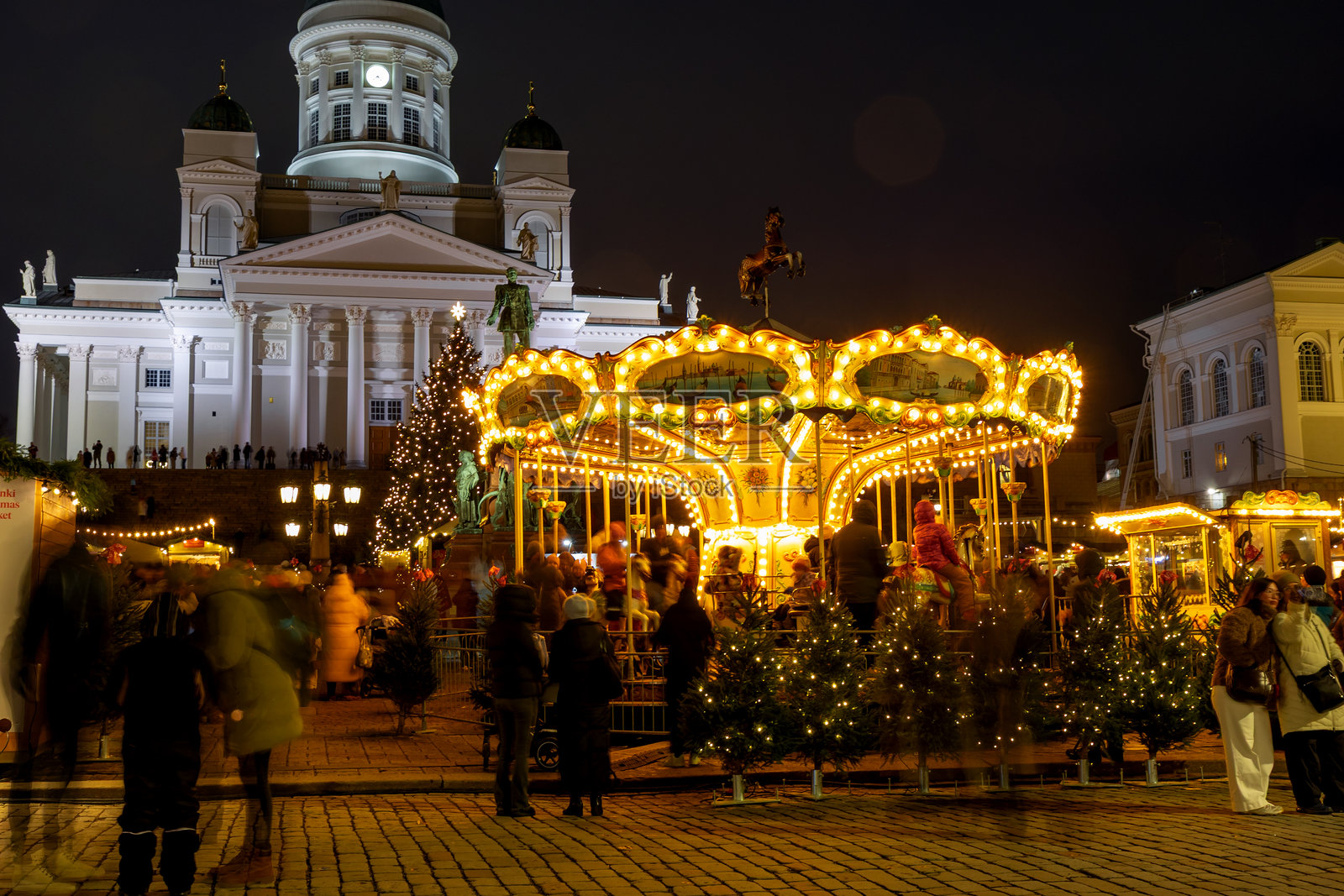 赫尔辛基圣诞集市(Tuomaan Markkinat),背景为参议院广场和赫尔辛基大教堂。节日摊位、假日灯饰、芬兰美食、手工艺品、复古旋转木马,游客和参观者云集。照片摄影图片