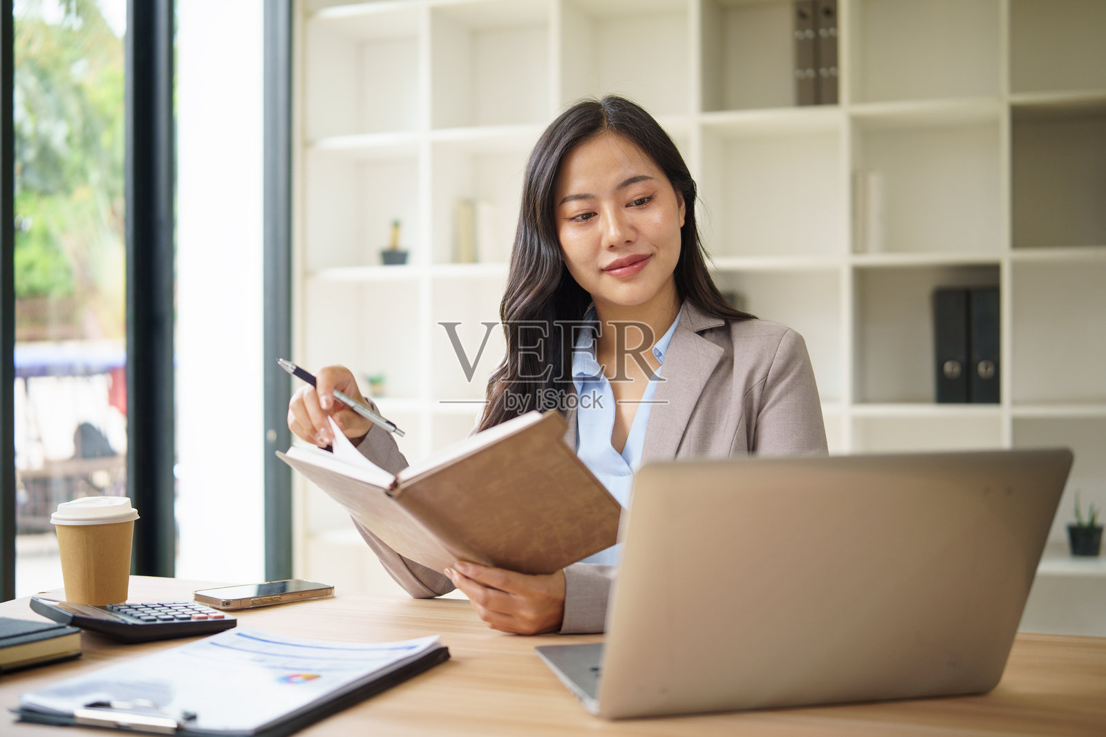 年轻的办公室职员在现代工作场所使用笔记本电脑规划商业策略。照片摄影图片