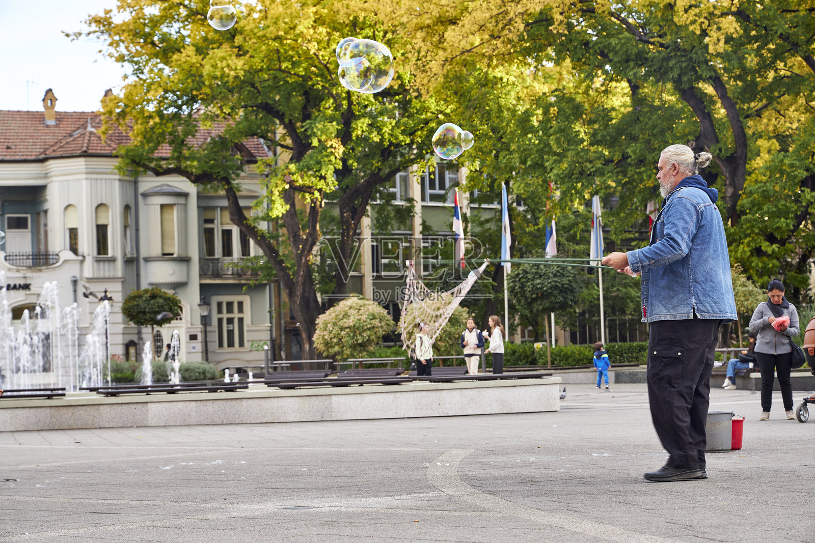 苏博蒂察街景，街头艺人在城市喷泉附近吹出巨大的肥皂泡，孩子们在充满活力的城市氛围中开心地追逐着五彩斑斓的泡泡。照片摄影图片
