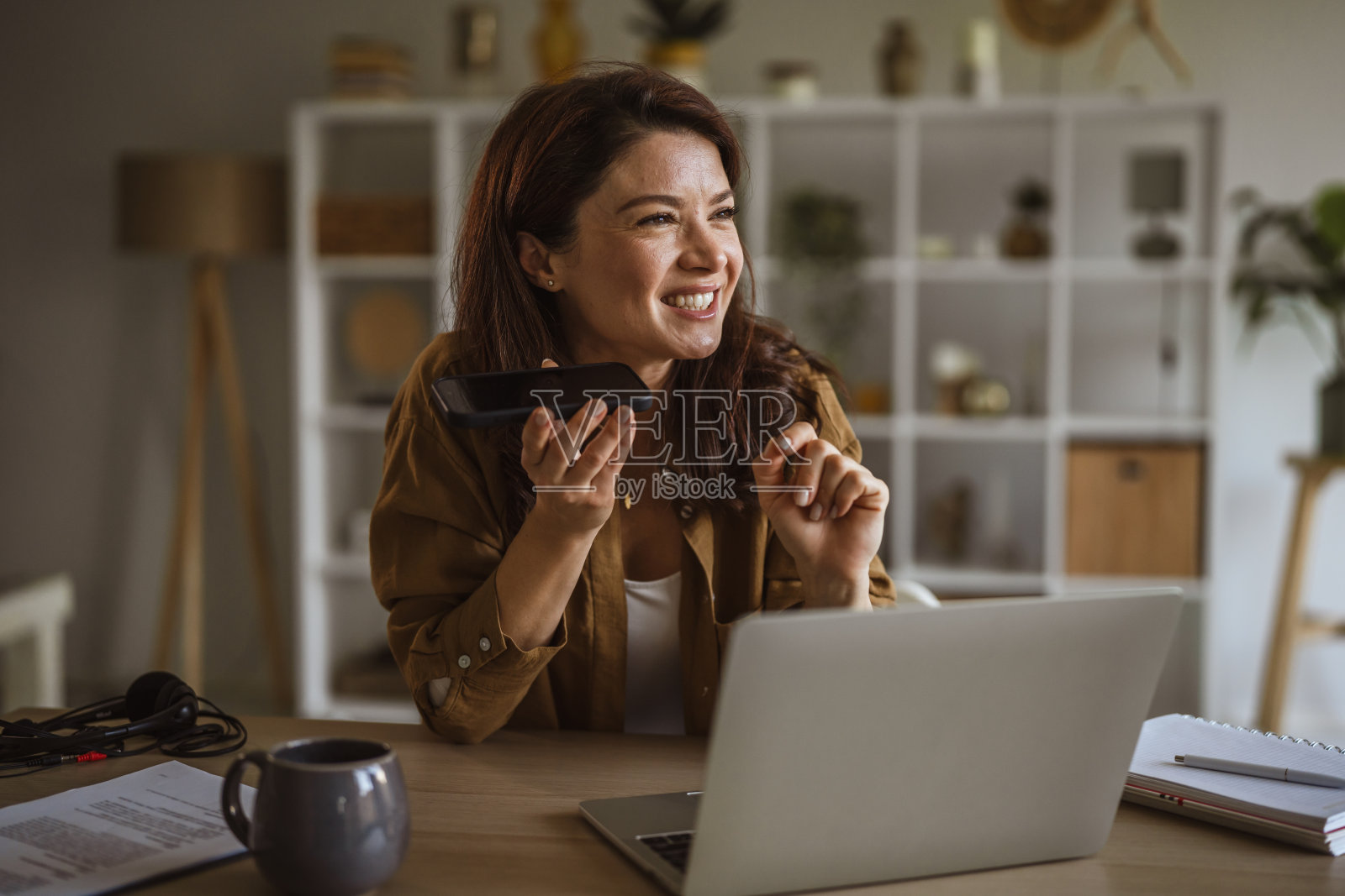 在家办公时用免提电话交谈的女士照片摄影图片