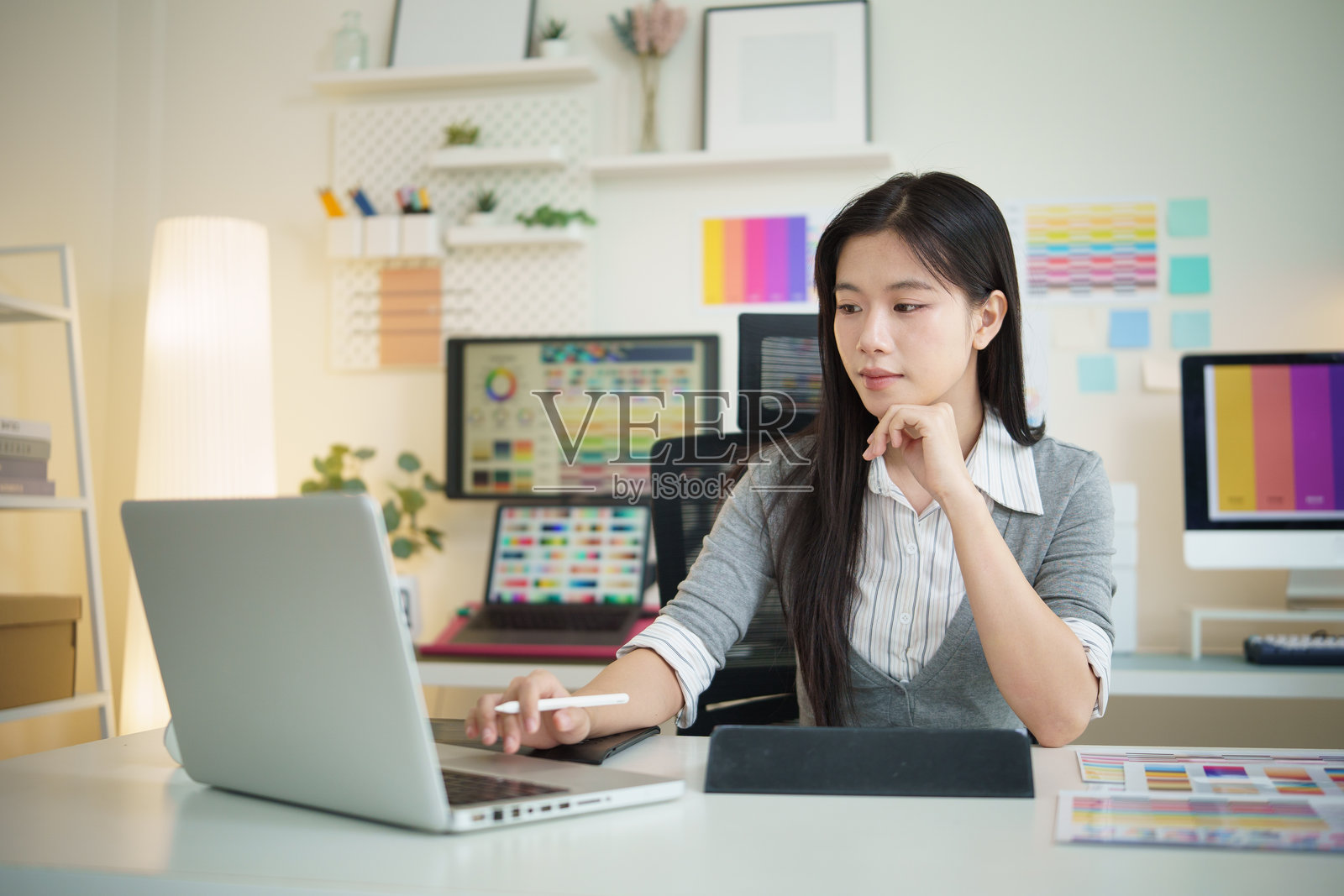 年轻的女平面设计师在现代创意办公室使用笔记本电脑工作。照片摄影图片