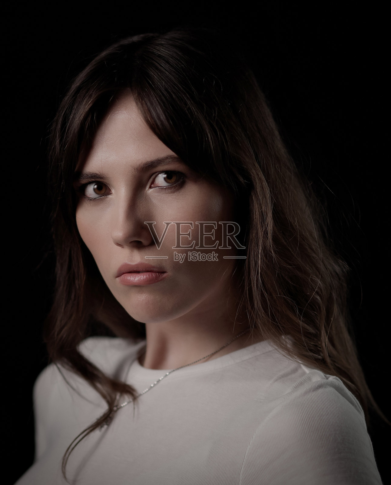 年轻美丽的女子在影棚里摆出严肃的表情照片摄影图片