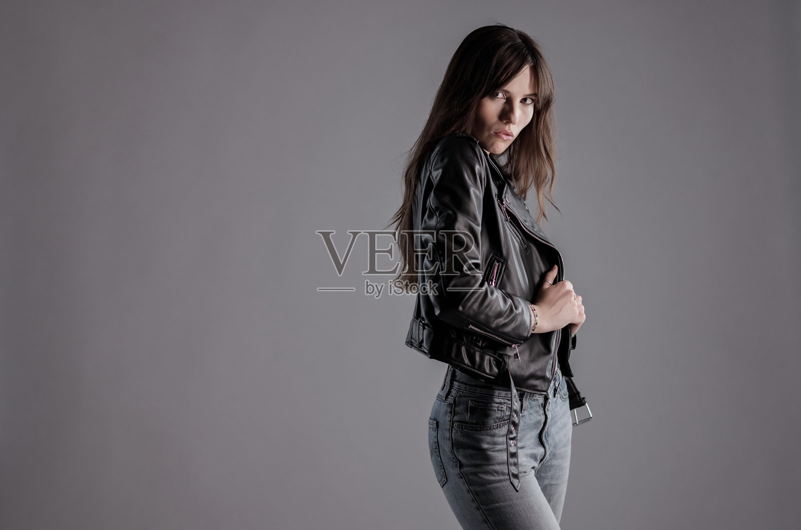 自信的年轻女子，身穿黑色皮夹克，正在摆姿势照片摄影图片