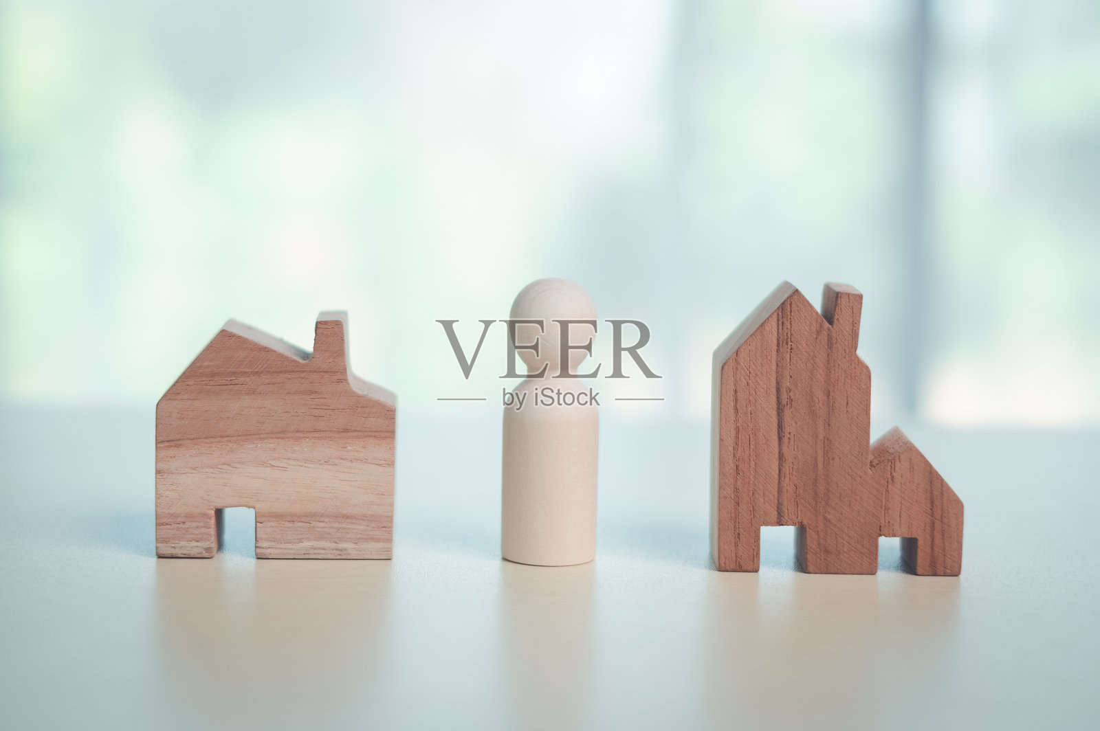 木制人偶站在两个房屋图标之间，代表着选择房产、住房决策、房地产投资、购房选项、保险规划和财务决策的概念。照片摄影图片