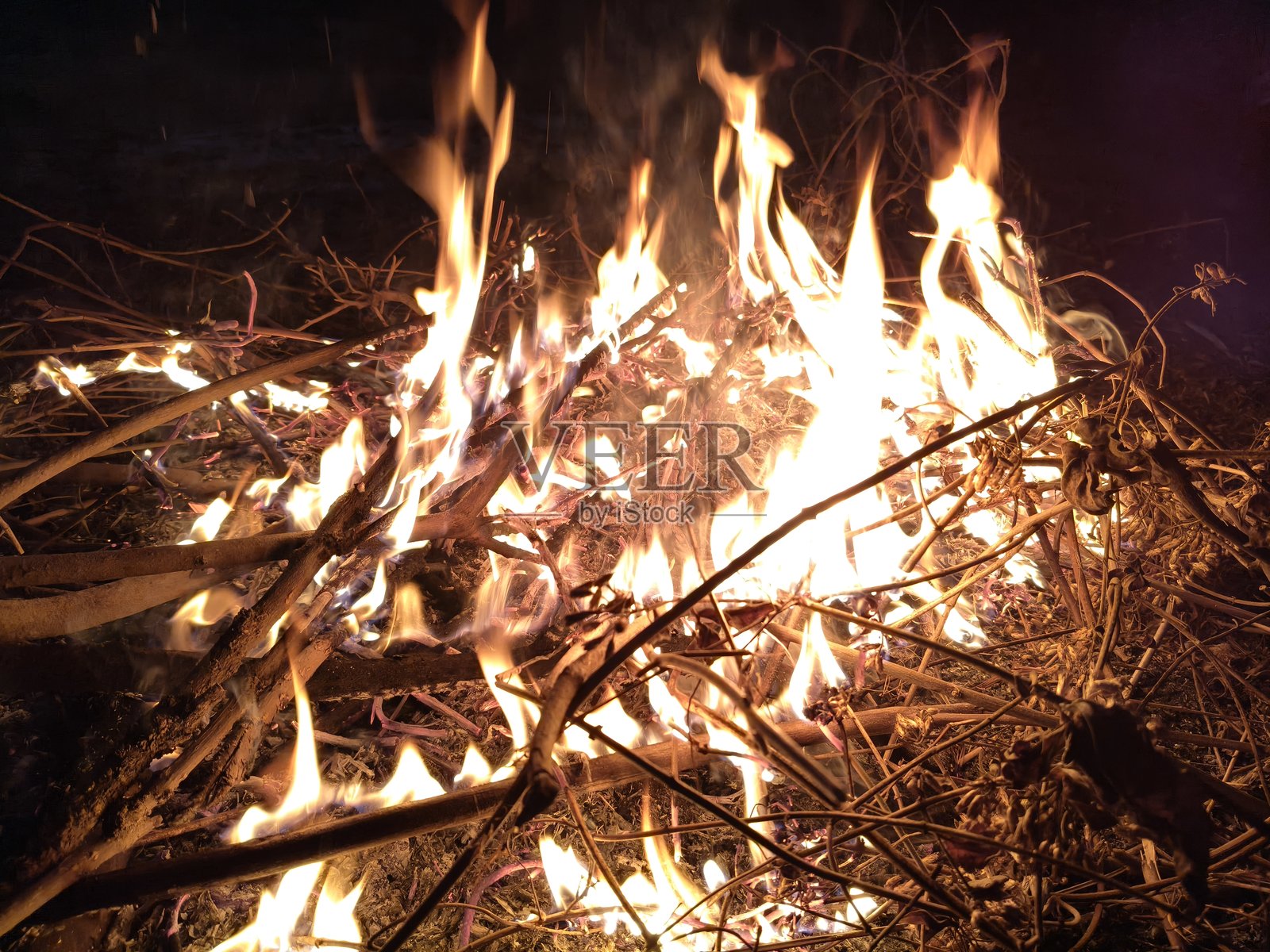 人们围坐在篝火旁，烘烤着双手和双脚。照片摄影图片