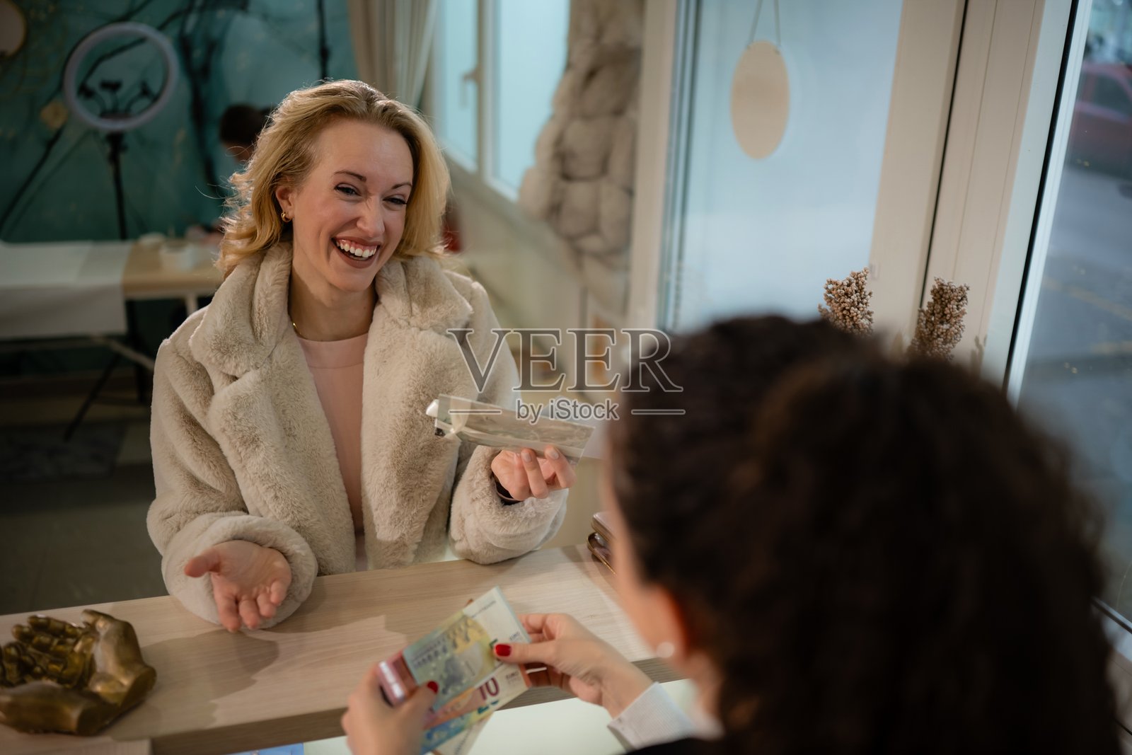 快乐的女士在柜台用现金支付购买的商品照片摄影图片