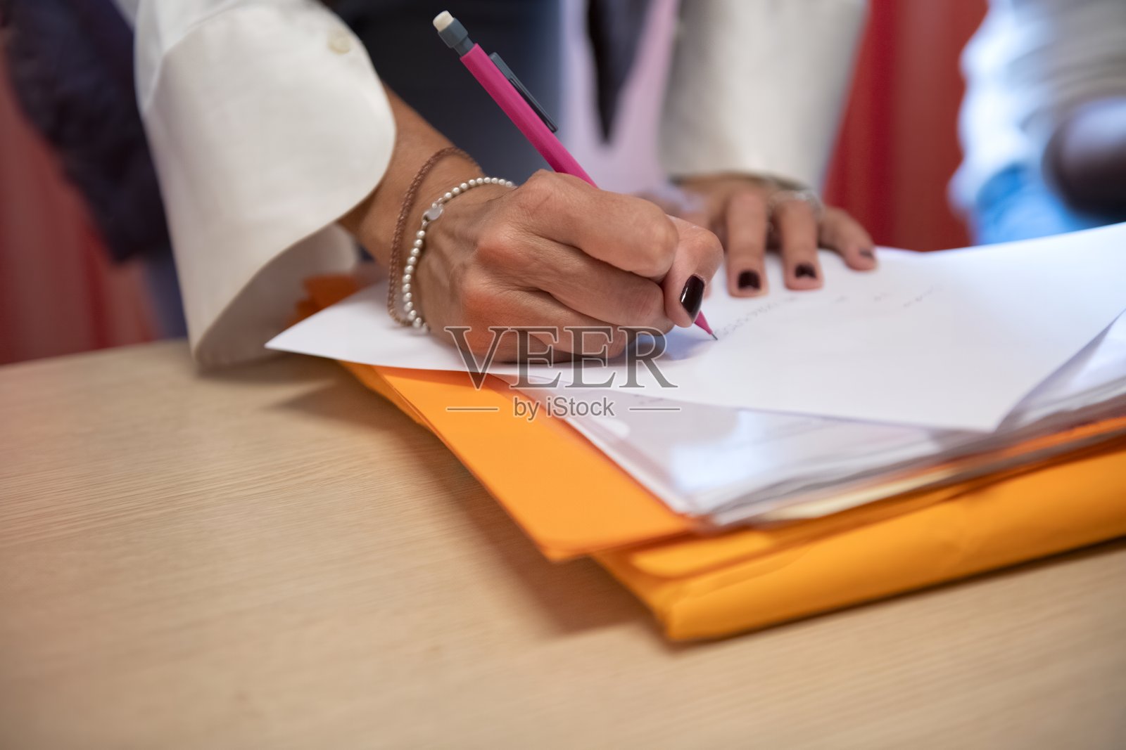 一位女士在干净整洁的专业办公室环境中工作时在笔记本上写字照片摄影图片