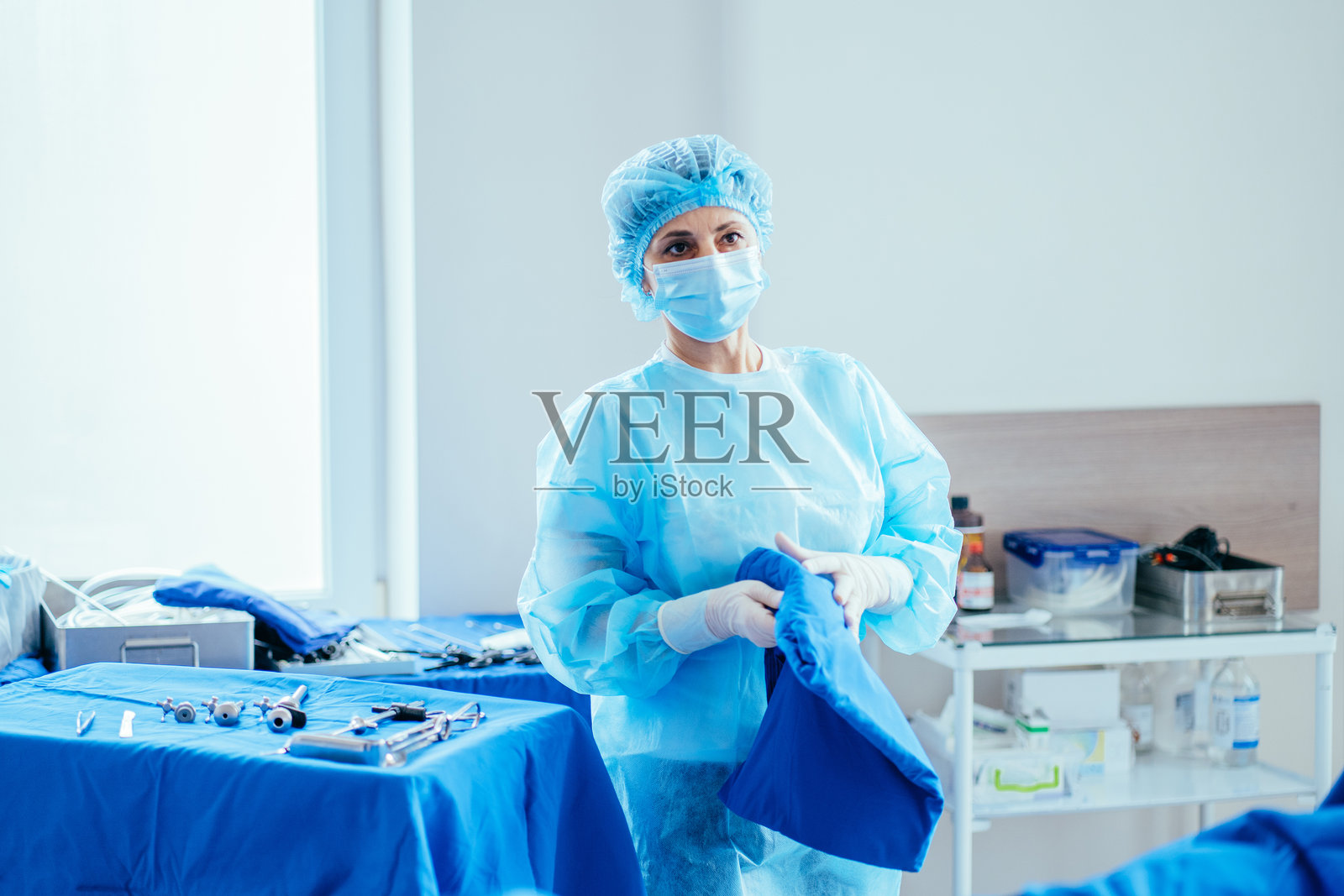 在手术室里，一名女助理手持腹腔镜手术器械，准备进行腹腔镜手术照片摄影图片