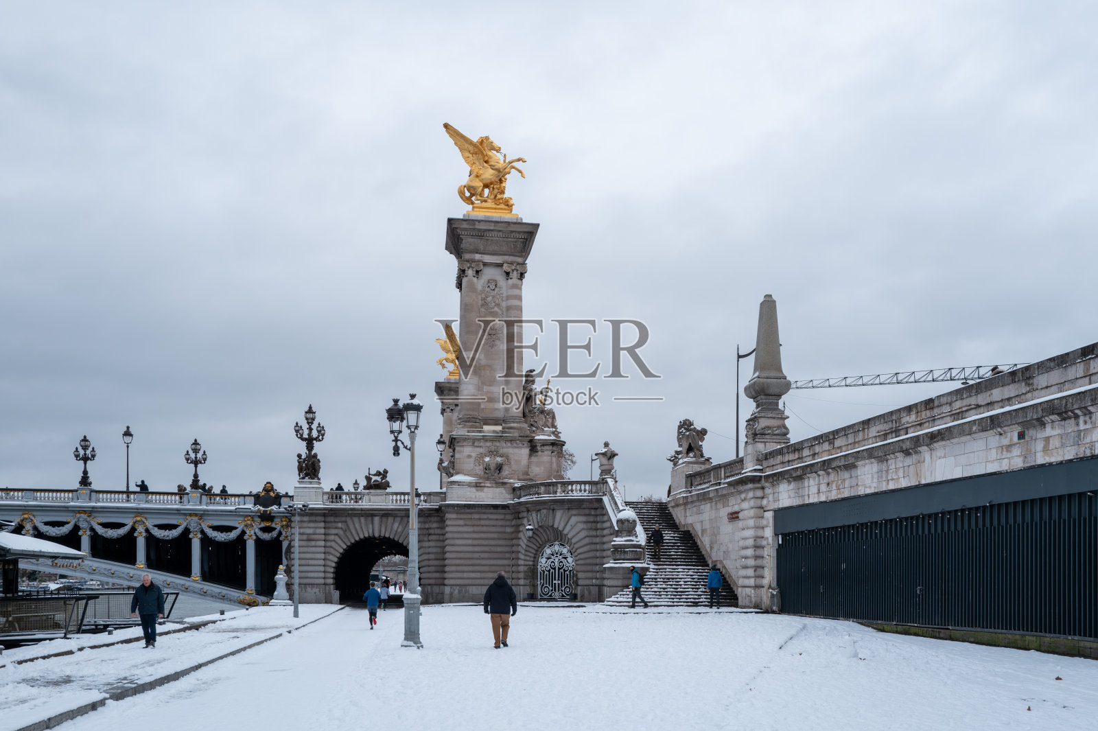 法国巴黎，亚历山大三世桥，积雪覆盖的码头和行人。照片摄影图片