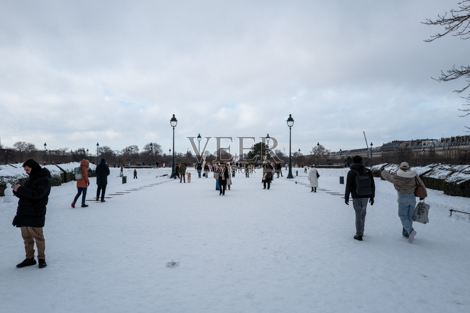人们走在巴黎杜乐丽花园被雪覆盖的道路上。照片摄影图片