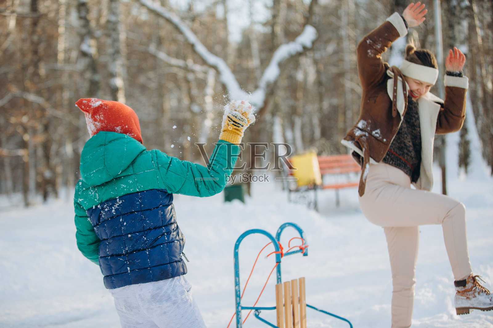 妈妈和孩子在冬天享受打雪仗的乐趣照片摄影图片