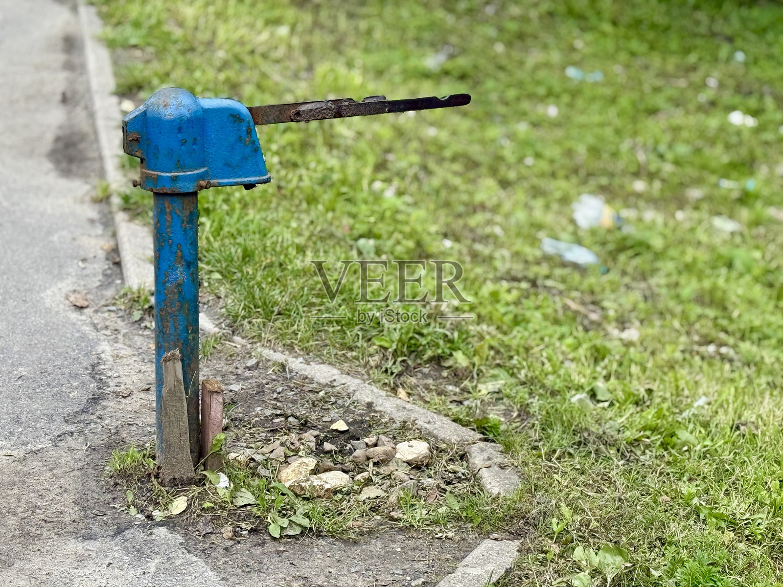 乡村水源，古老的铸铁水泵在黎明时分的乡村杂草丛生中，一个古老的铸铁水泵独自矗立在龟裂的水泥地上，在宁静的乡村早晨照片摄影图片