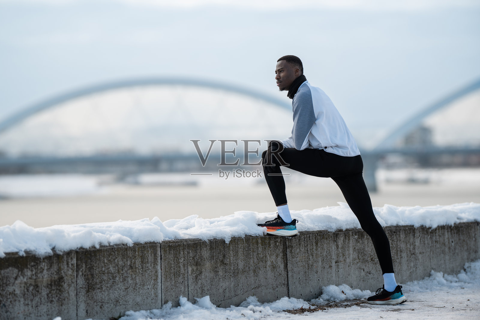 一名男性跑者在河边进行冬季户外训练时拉伸照片摄影图片