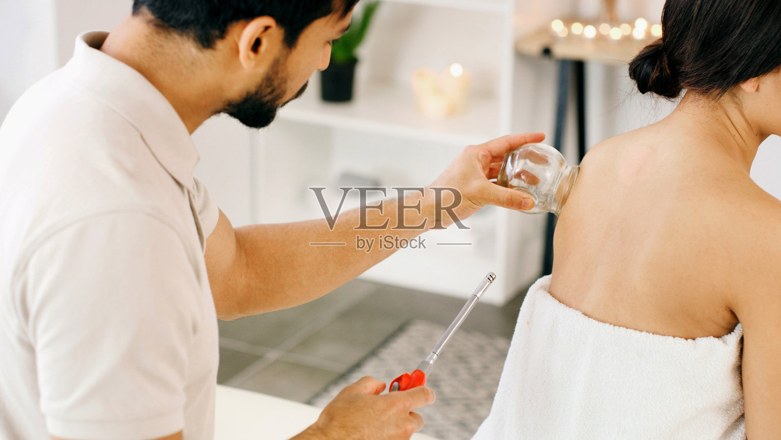 人们、玻璃和拔罐疗法用于缓解背部疼痛，促进肌肉血液流动，有益于健康和康复。理疗师、整体水疗中心以及一位女士与一位男士进行健康、放松或度假，享受深层组织按摩。照片摄影图片