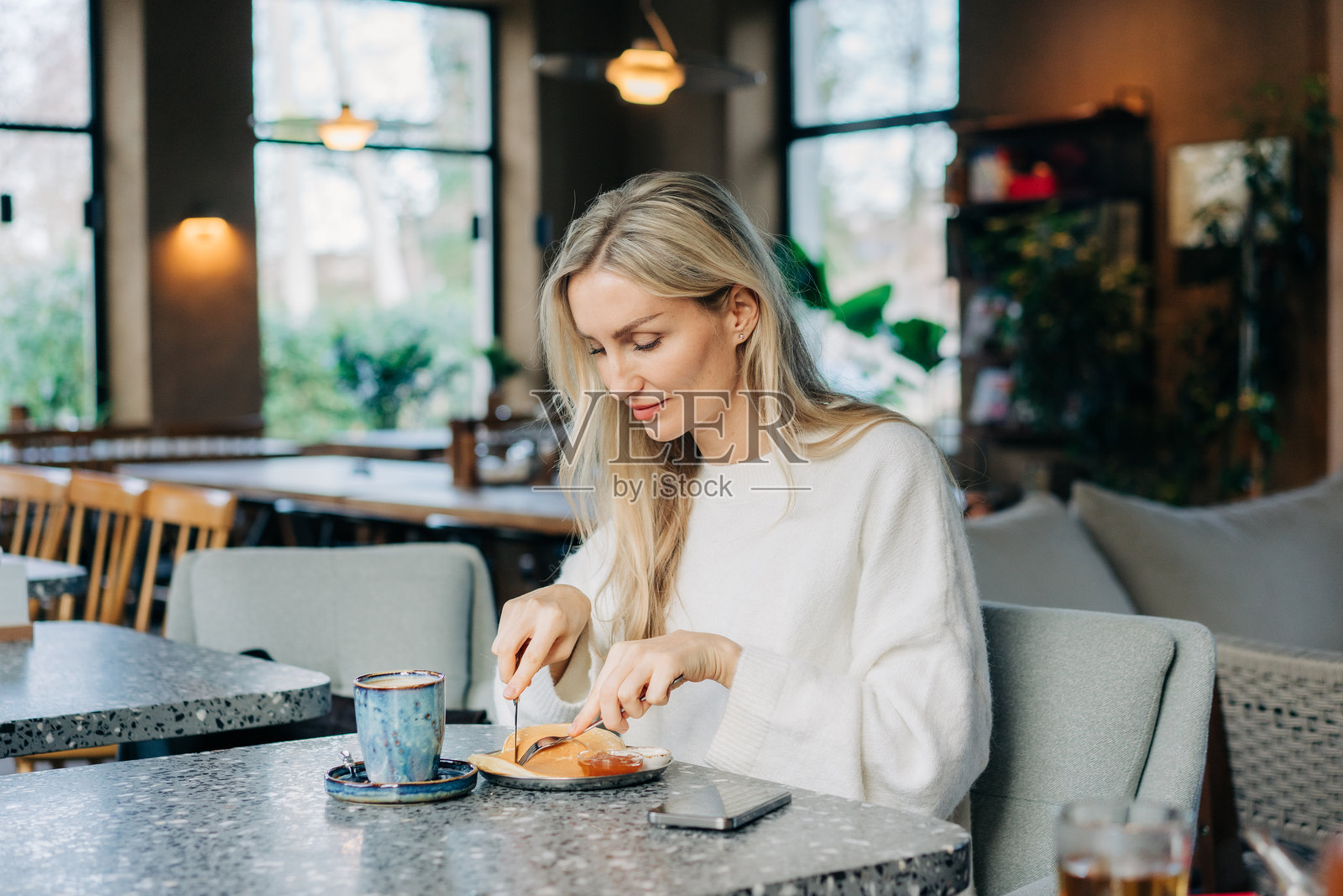 一位饥饿的美丽女子正在咖啡馆享用煎饼早餐。照片摄影图片