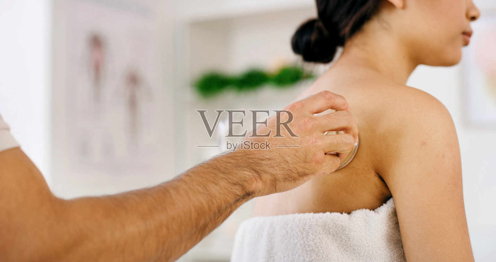 拔罐疗法用于缓解背部疼痛，放松肌肉，促进血液循环，带来健康益处。理疗师为女性进行整体水疗，手部按摩，促进健康，或在度假村进行深层组织按摩。照片摄影图片