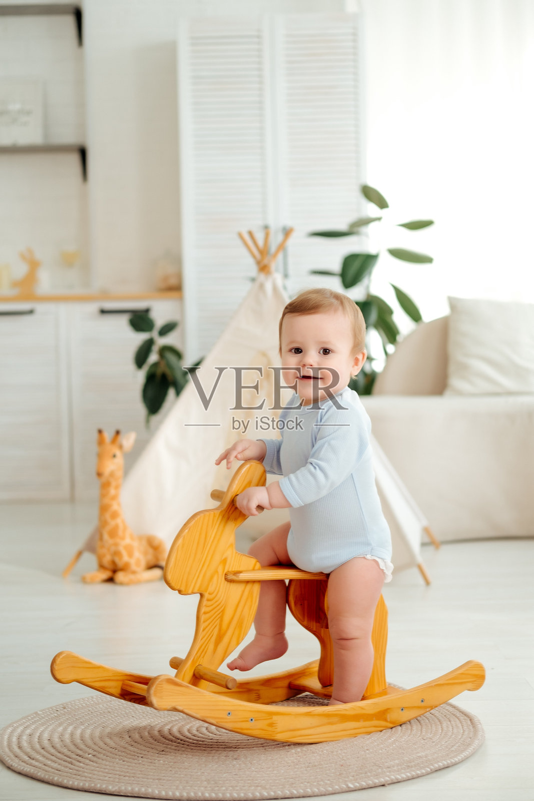一个男婴在玩木马，一个小孩在家玩耍，早期儿童发展，一个孩子在家的儿童房里玩耍照片摄影图片