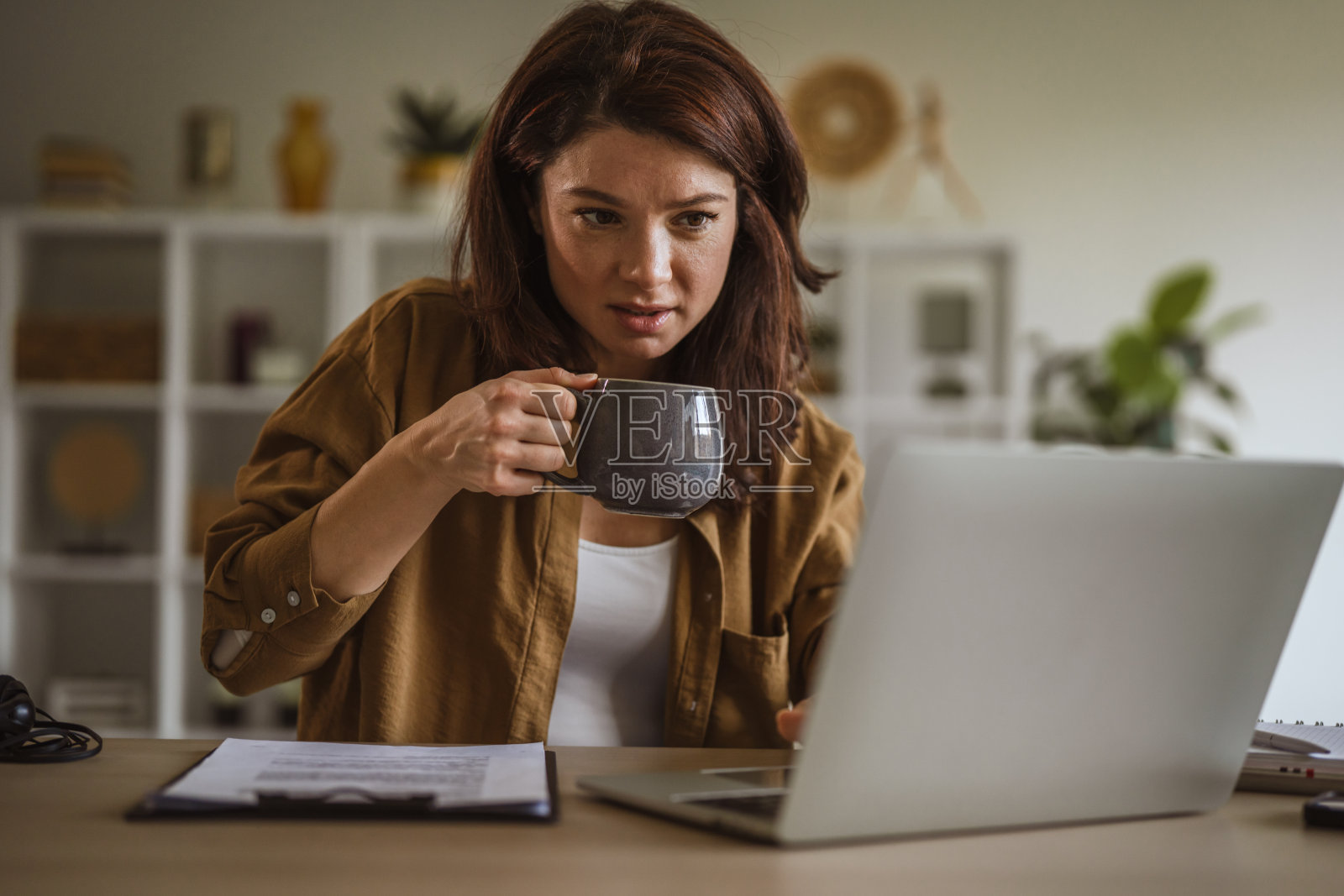 女性在家中的家庭办公室远程工作，同时喝着咖啡照片摄影图片