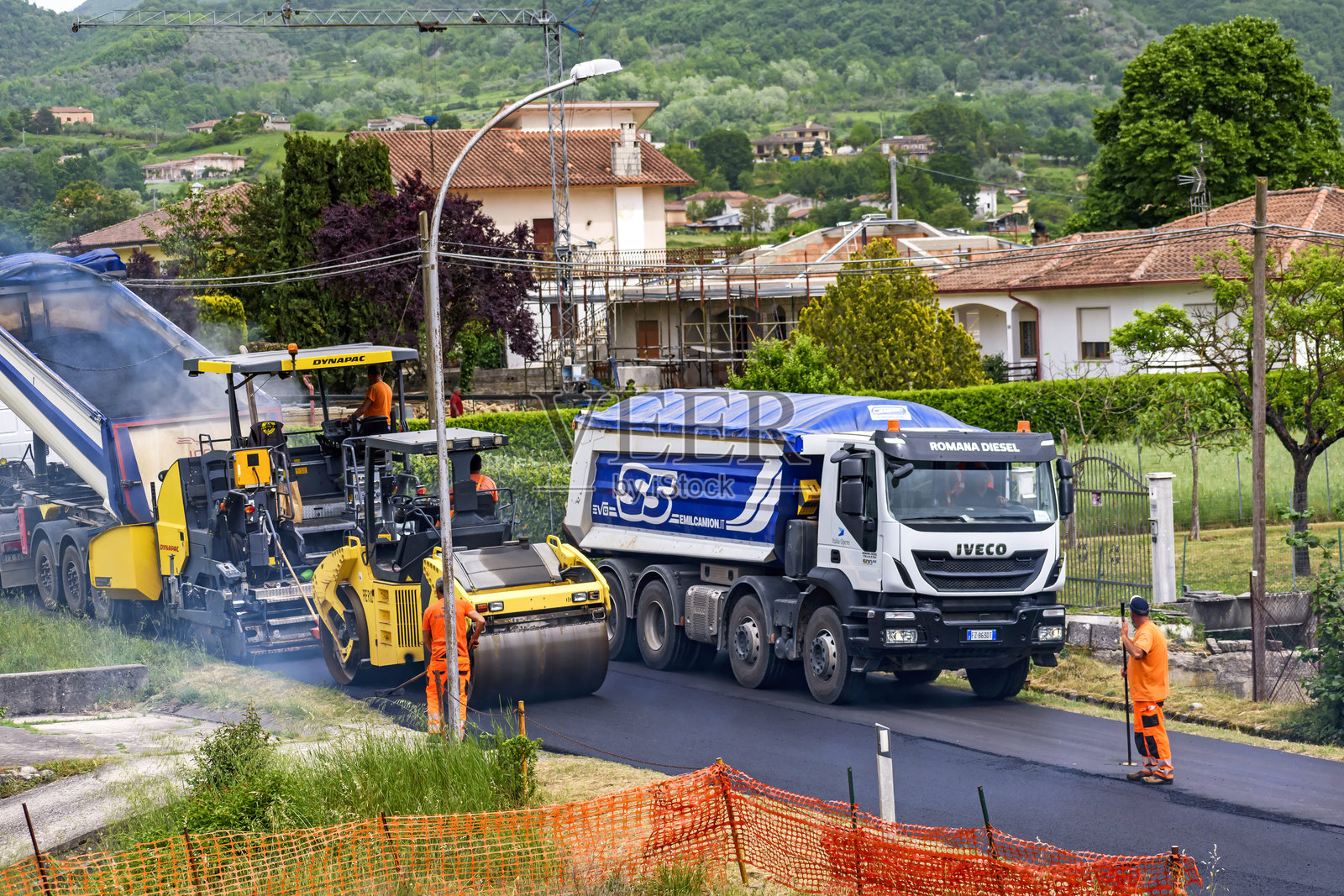男人们在公路上铺设沥青,有工业车辆和机械在作业。照片摄影图片