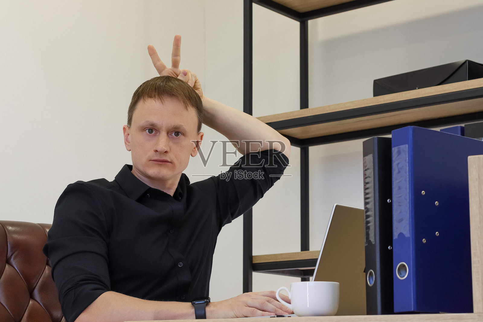 年轻的职业人士在头顶上做出胜利手势照片摄影图片