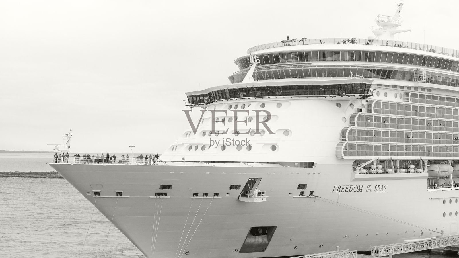 大型游轮“海洋自由号”停靠在港口，乘客们正从甲板上欣赏美景。年度代表色：云舞者照片摄影图片