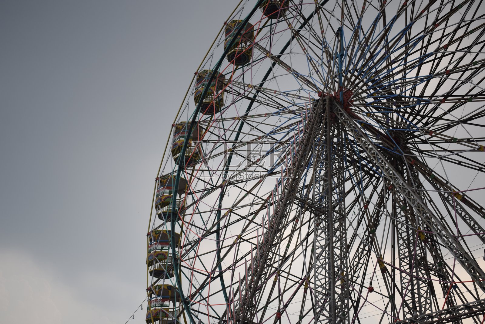 特写印度德里杜塞拉嘉年华上色彩缤纷的摩天轮。摩天轮秋千的底部视角。傍晚时分，装饰着彩色座舱的摩天轮。照片摄影图片