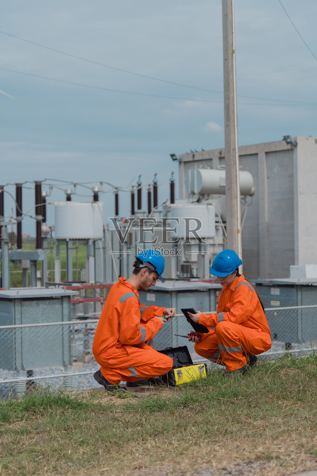 电气工程师正在变电站内检查风力发电场输送过来的电力运行和配电系统。照片摄影图片