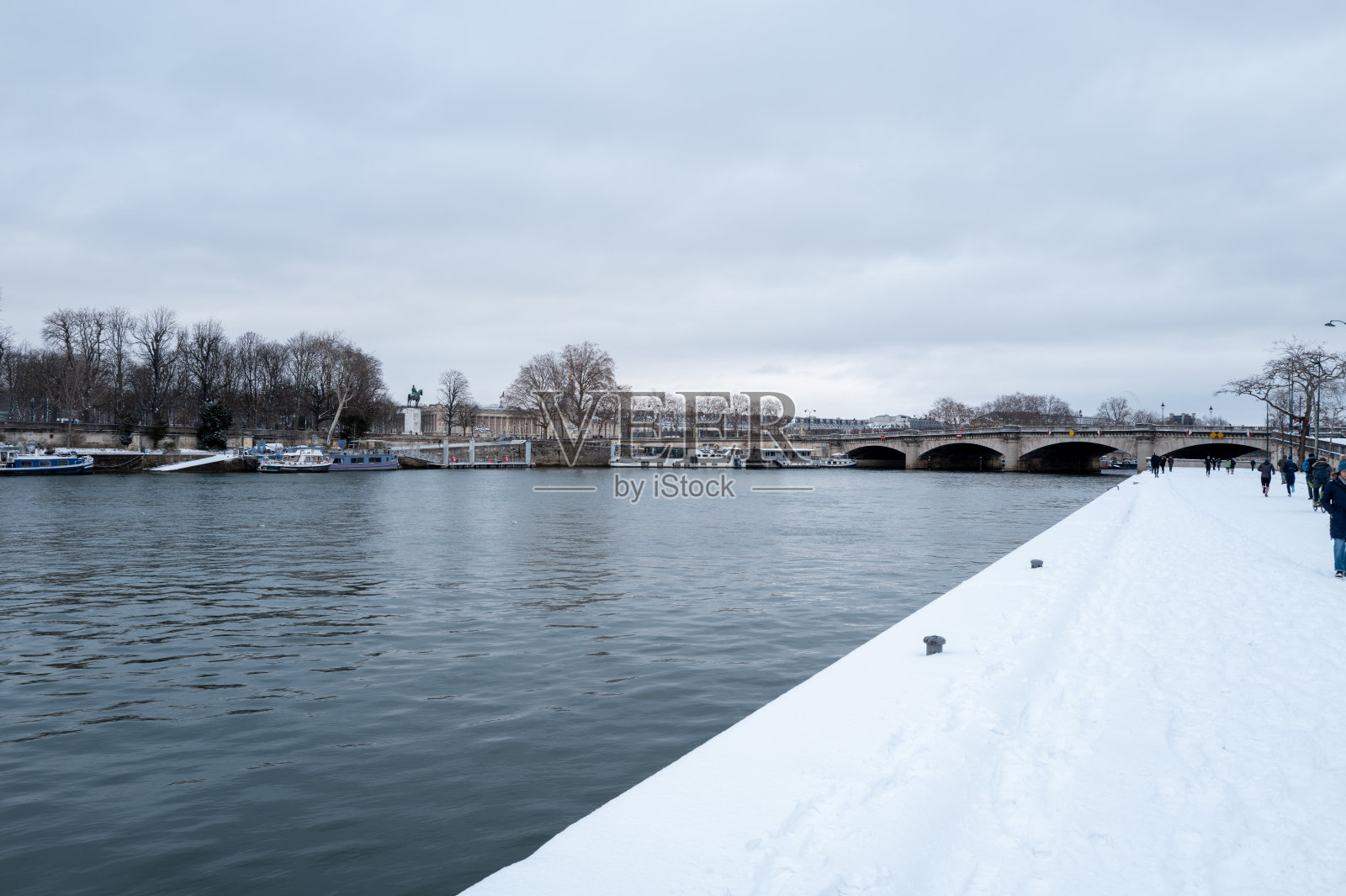 法国巴黎,塞纳河畔覆盖着白雪的码头,有行人和协和桥。照片摄影图片