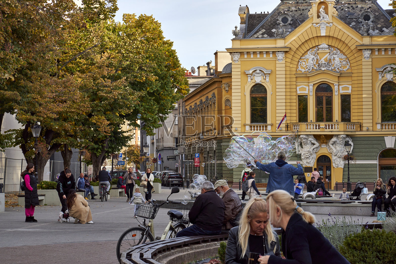 苏博蒂察街景，街头艺人在城市喷泉附近吹出巨大的肥皂泡，孩子们在热闹的城市氛围中开心地追逐着五彩斑斓的泡泡。照片摄影图片