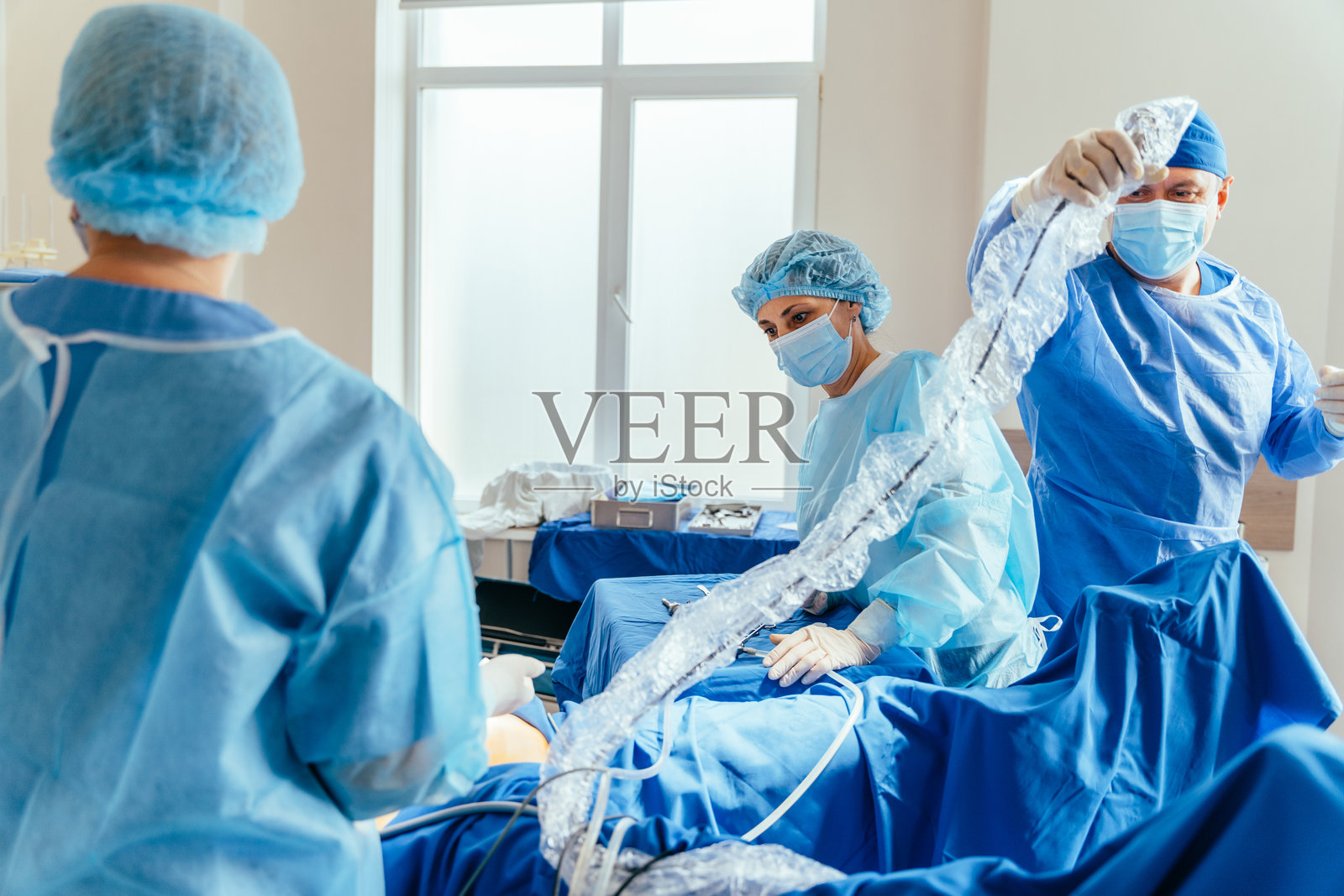 专注的医生身着防护服，在现代手术室中进行手术的肖像照片摄影图片