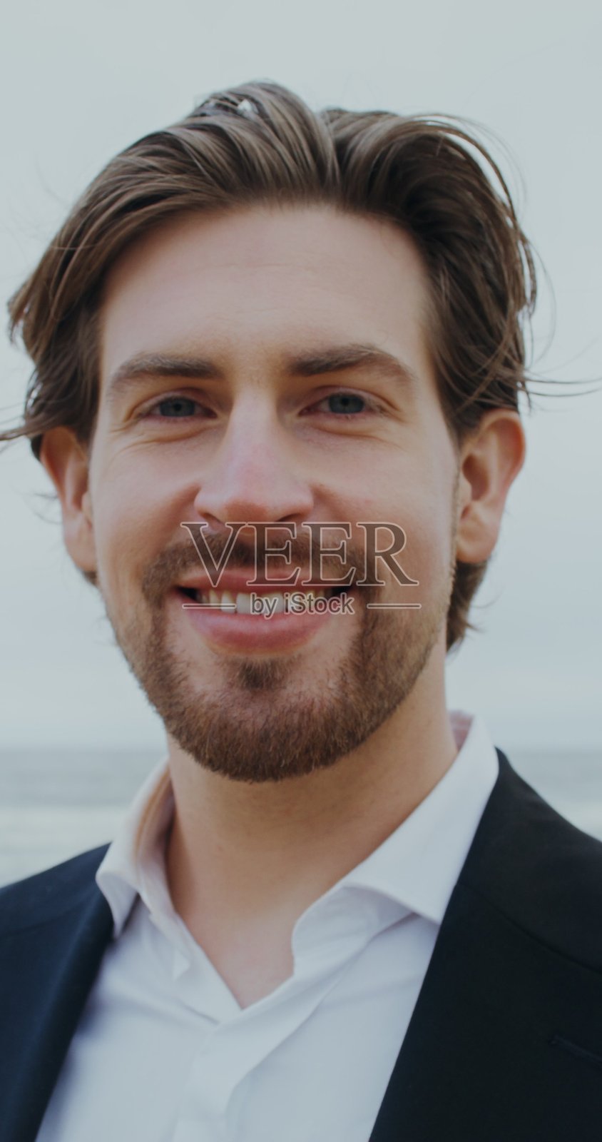 一位穿着正装的男士微笑着看向婚礼。照片摄影图片