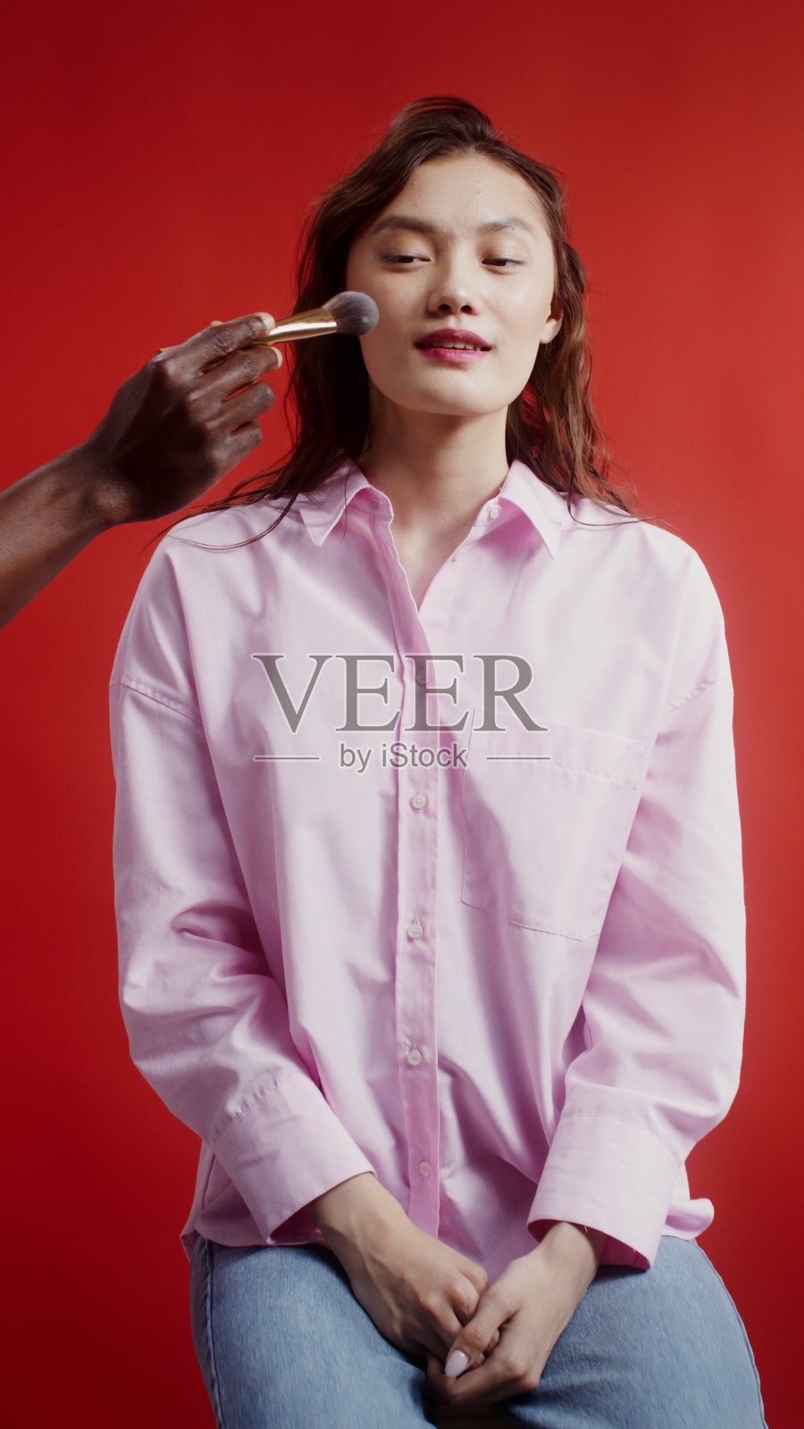 化妆师在女性脸上画腮红，竖图 - 模特照片摄影图片