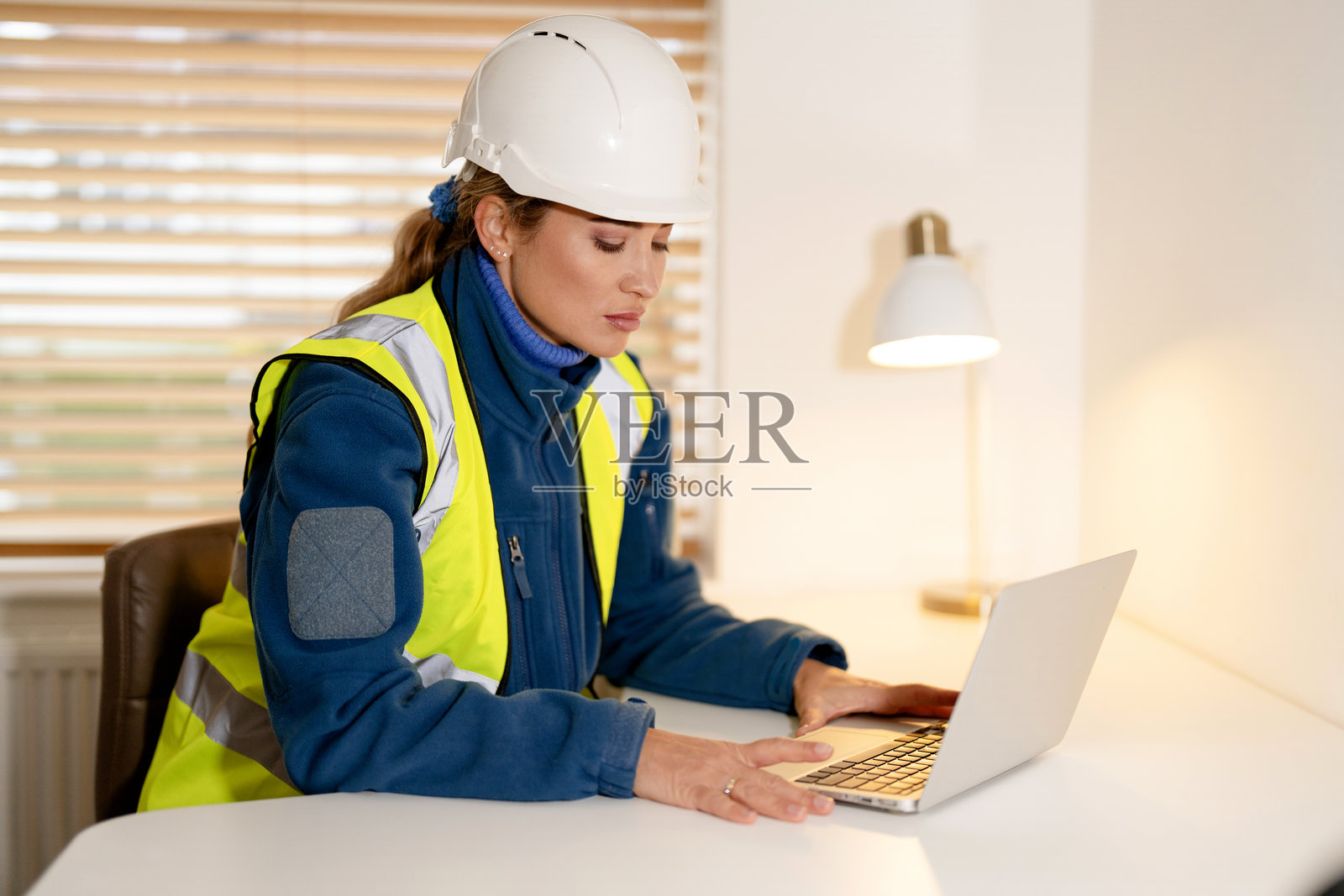 一位女性建筑工程师在办公室使用笔记本电脑和手机工作照片摄影图片