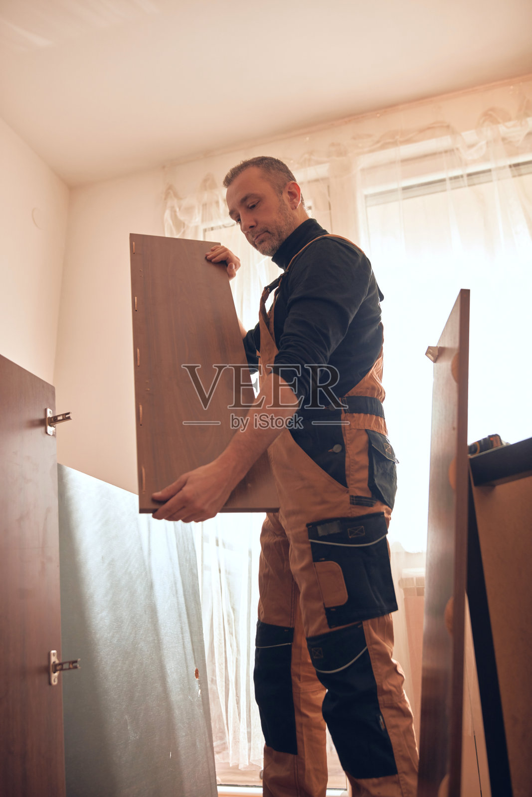 木匠在新公寓里工作并组装家具。照片摄影图片