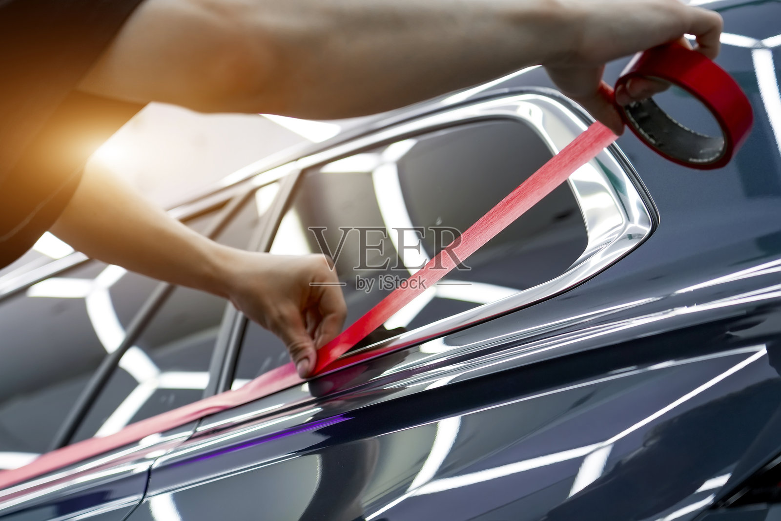 在汽车美容细节处理过程中，在靠近车门的玻璃框架上粘贴红色的保护胶带照片摄影图片