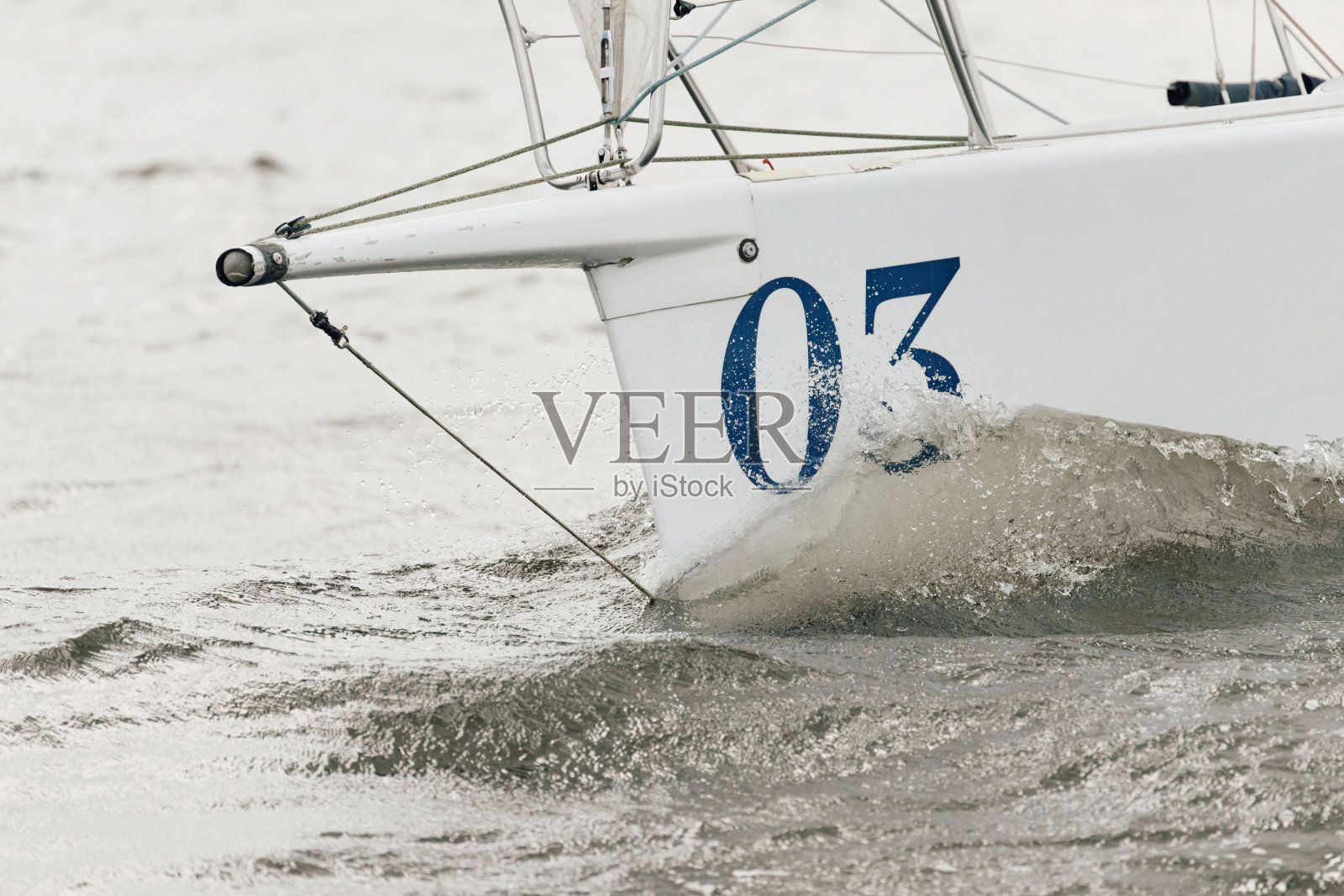 阳光明媚的一天，在芬兰湾的帆船赛中，一艘帆船的船头和船首斜桅，帆船正在比赛，船体下溅起水花，团队合作，登船照片摄影图片