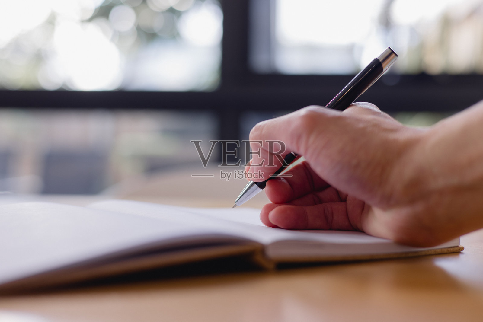 书写与创意概念，特写一只手拿着笔在有横线的笔记本上书写，象征着记录、计划、教育以及个人或专业文档。照片摄影图片