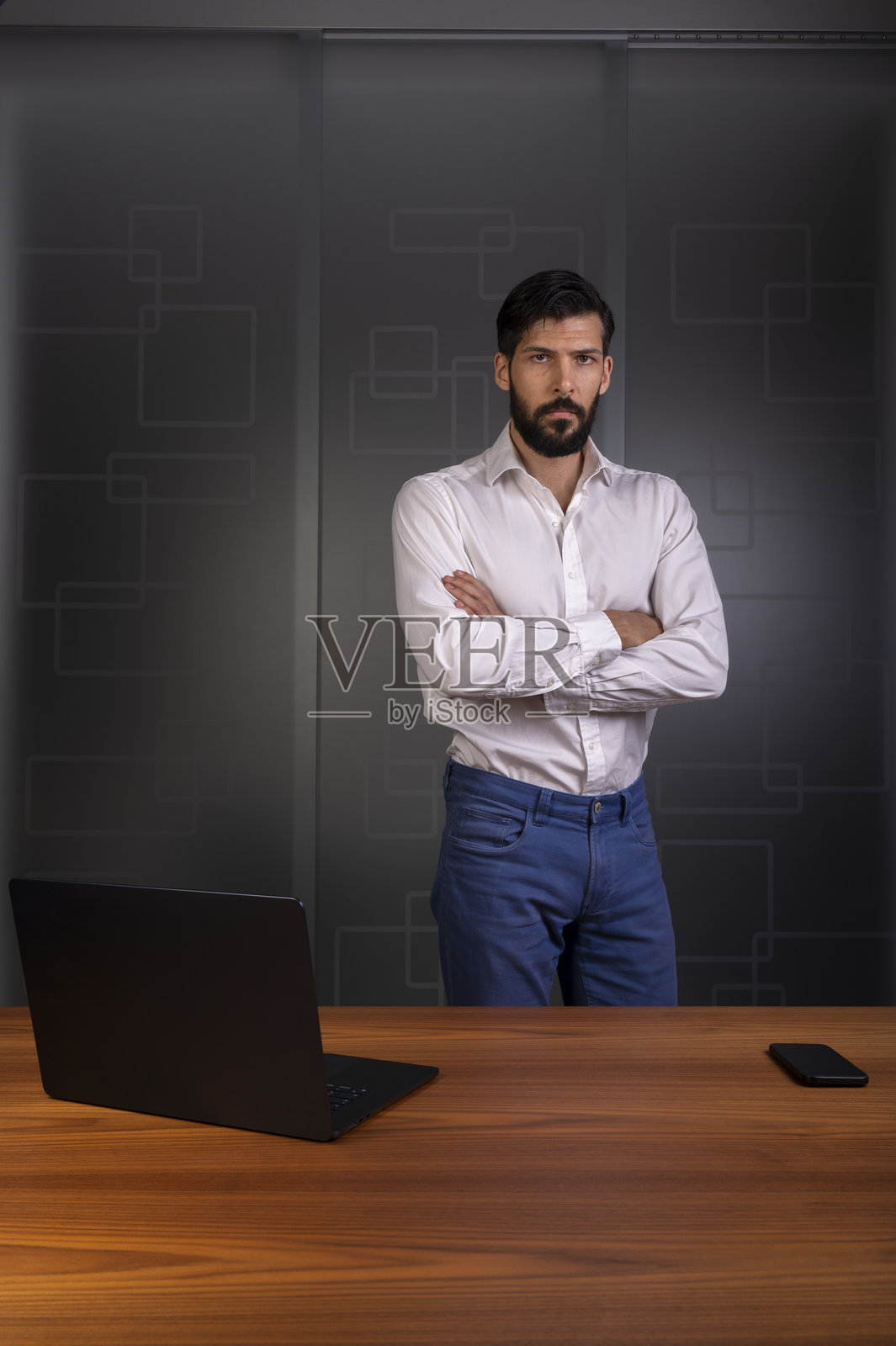 身着白衬衫和蓝色长裤的男子站在现代办公室，代表企业或公司照片摄影图片