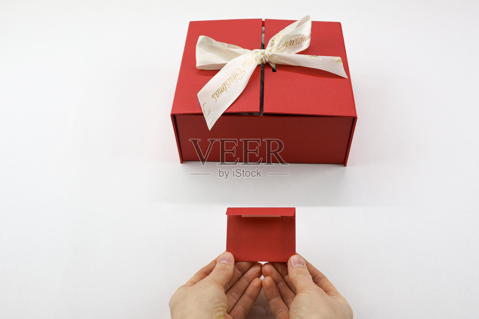 白色背景上，手中拿着的红色礼品盒和红色信封照片摄影图片
