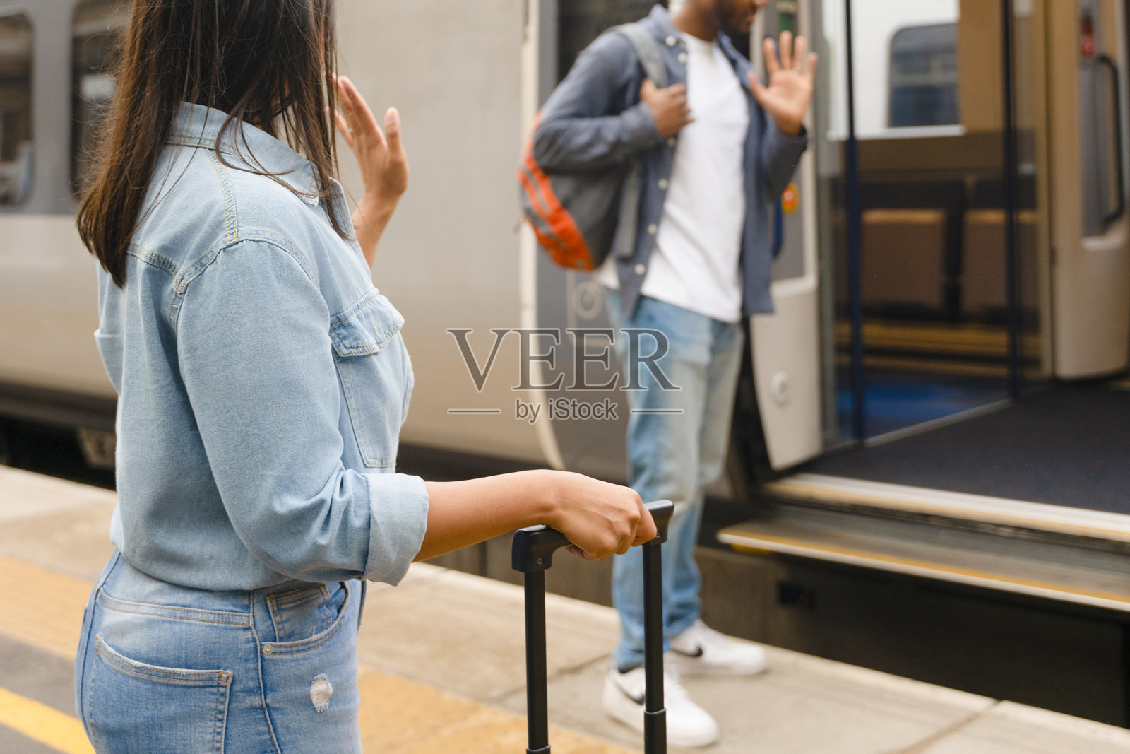 白天，一位女士在火车站向一位男士挥手告别照片摄影图片