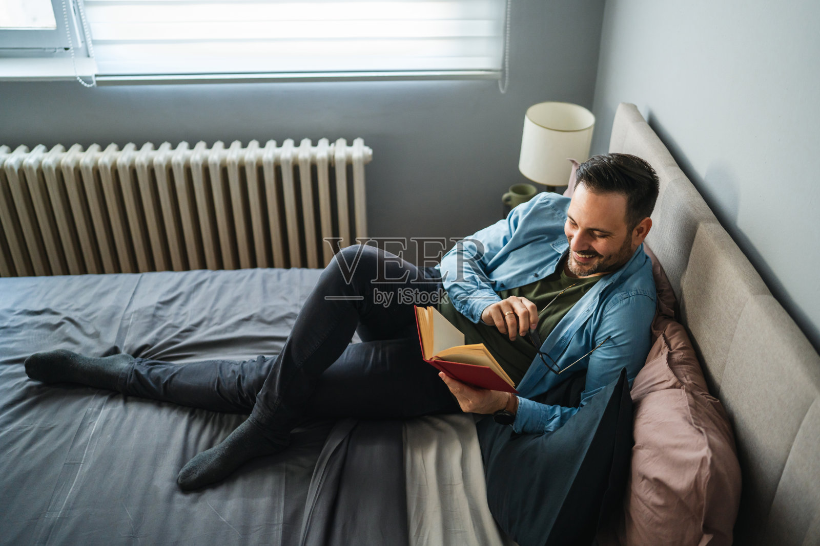 快乐的男人在床上享受休闲阅读时光照片摄影图片