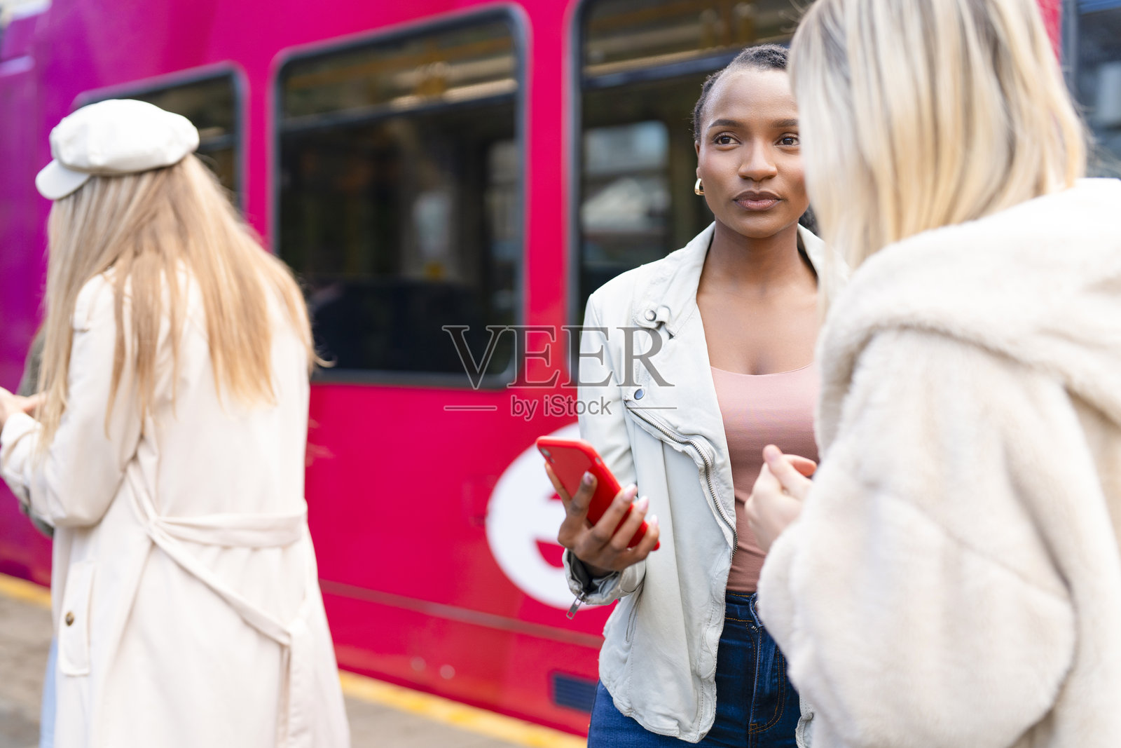 白天，朋友们在城市火车站使用手机等待照片摄影图片