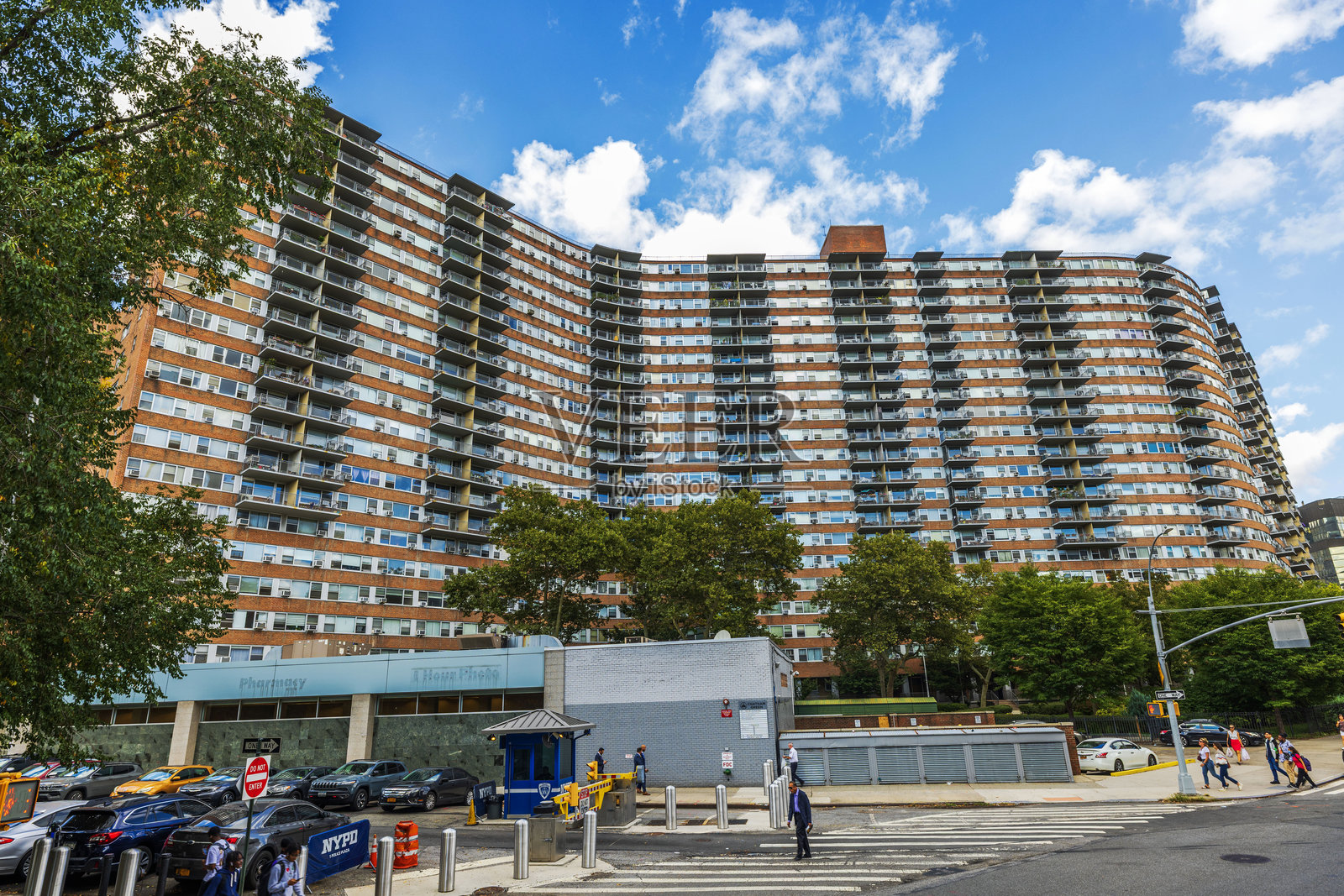 繁华曼哈顿街道上方，一座大型弧形住宅楼设有阳台，享有美丽的城市景观，街上行人如织。照片摄影图片