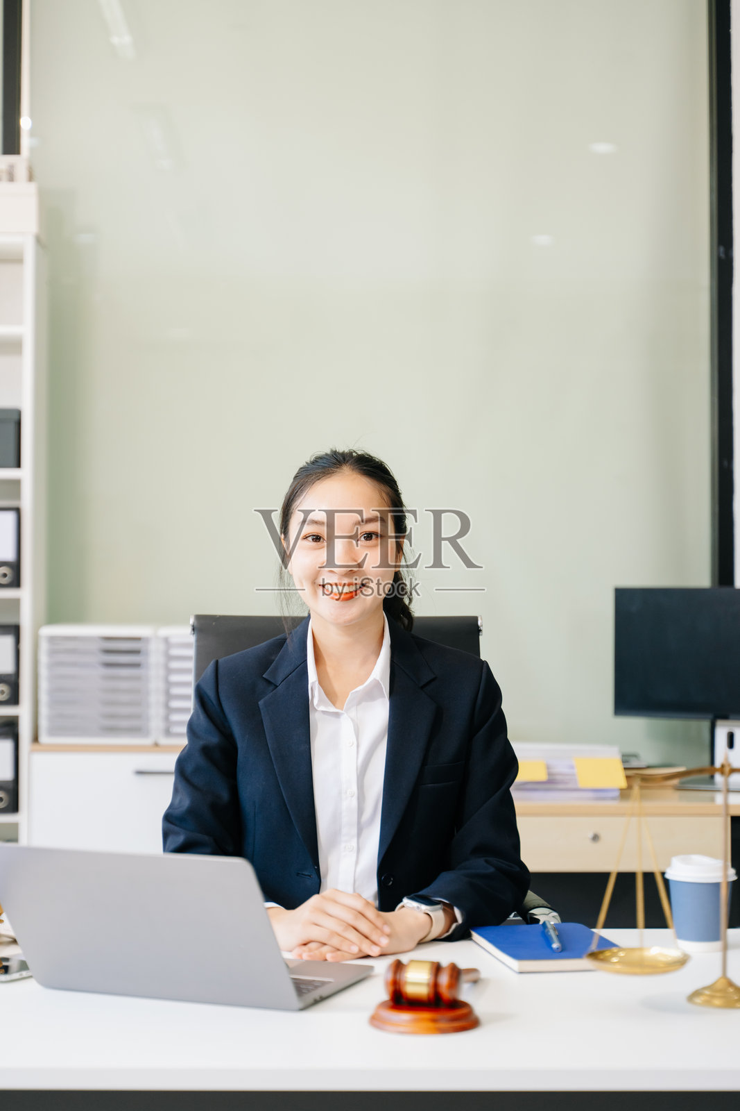 女律师在办公桌前庆祝成功，桌上有文件、法槌和天平照片摄影图片