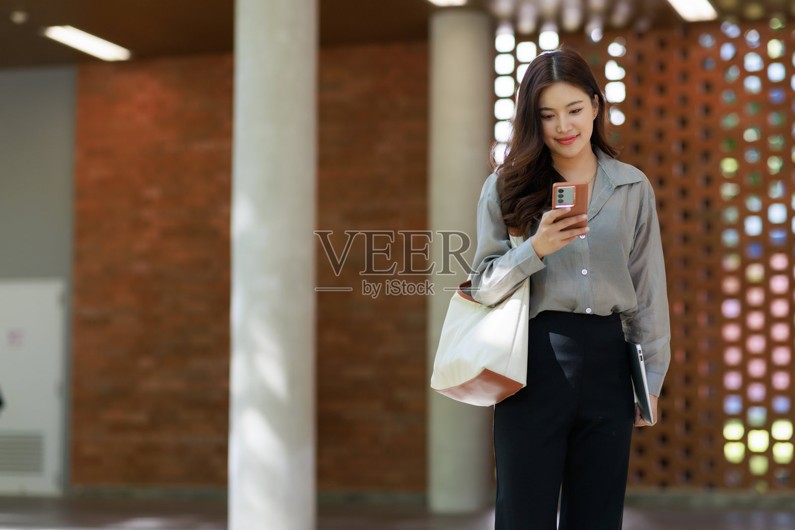 年轻女子一边走路一边看手机照片摄影图片