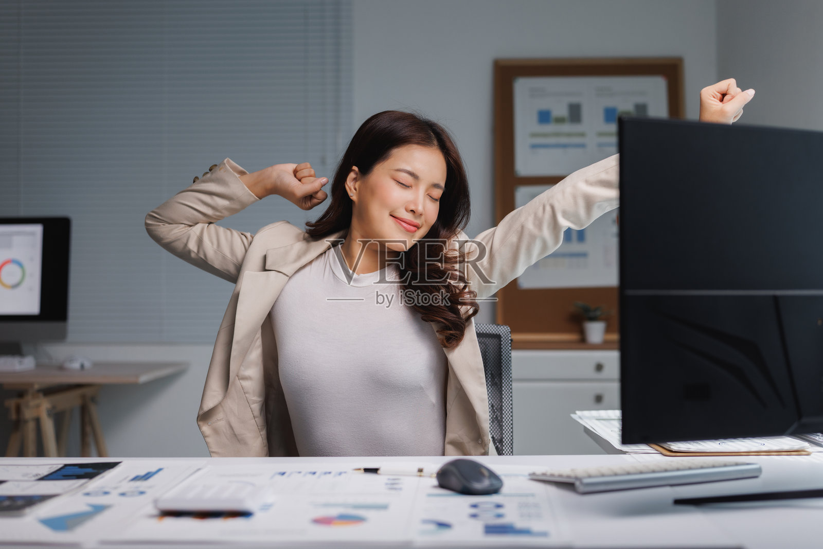 女商人在黑暗的办公室加班后伸展身体照片摄影图片